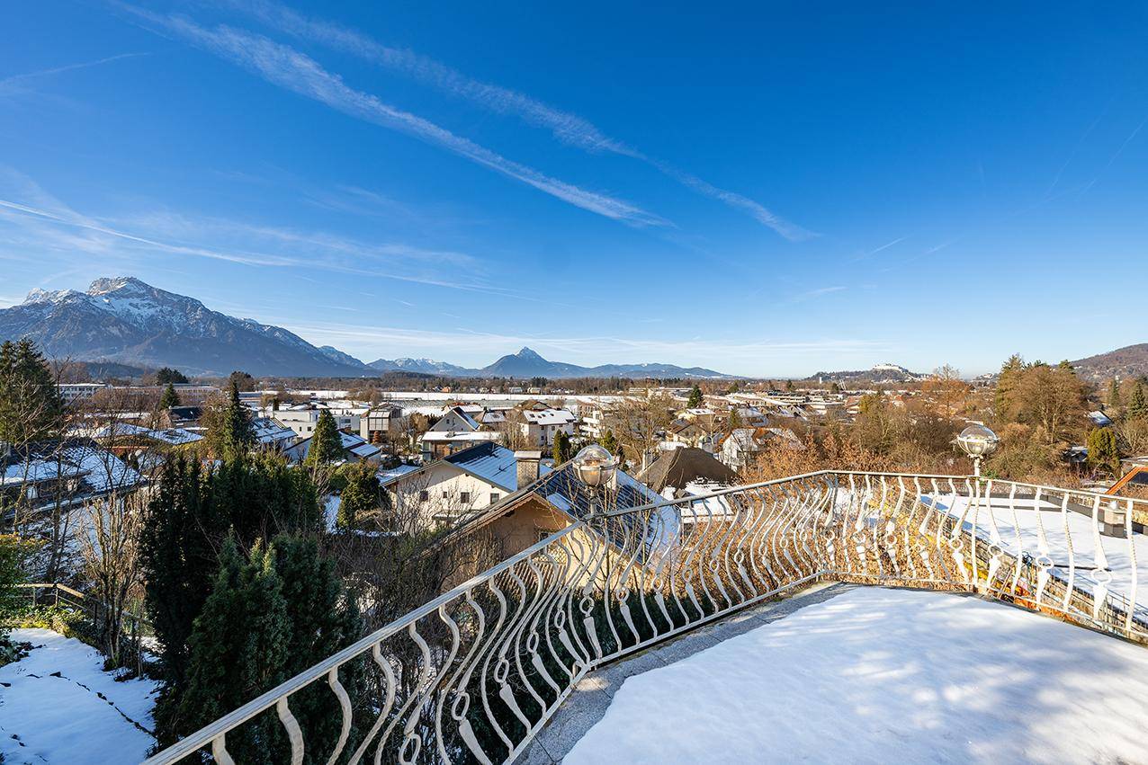 Großer Balkon mit schmiedeeisernem Geländer und weitem Blick über die verschneite Landschaft und Berge.