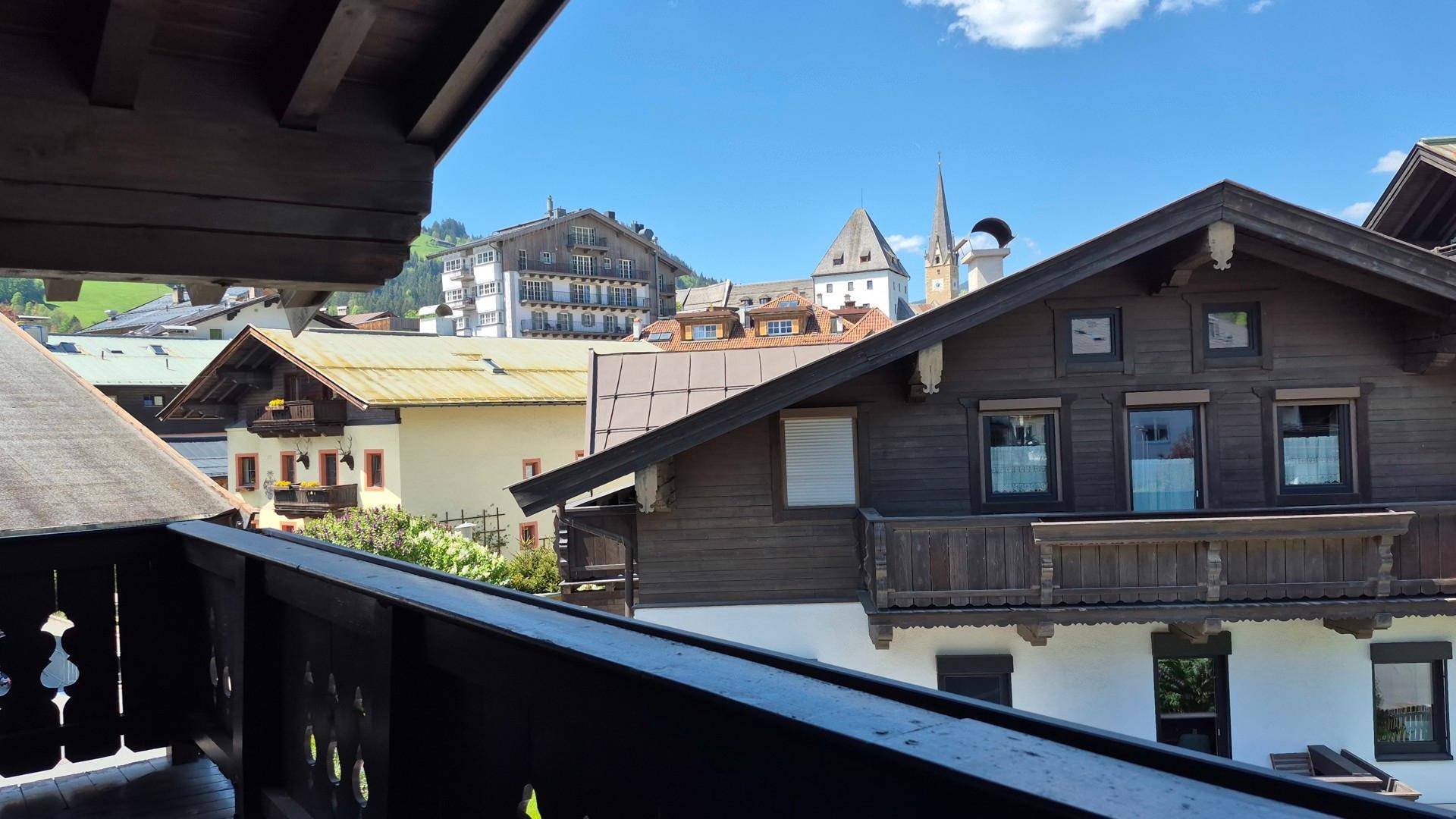 Blick vom Balkon auf traditionelle Gebäude und den Kirchturm einer charmanten Alpenstadt.