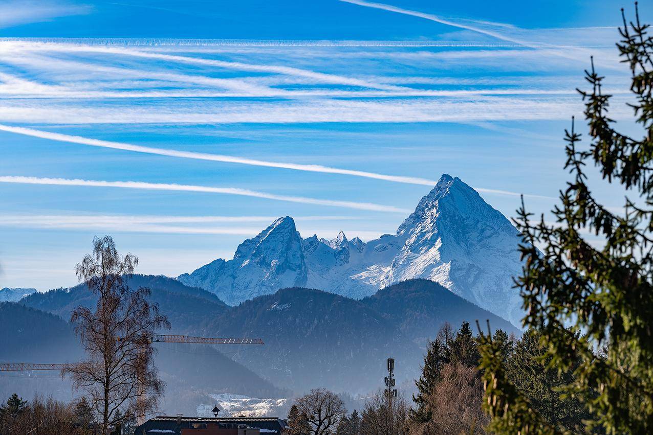 Beeindruckender Blick auf schneebedeckte Berggipfel und weite Wälder unter klarem Winterhimmel.