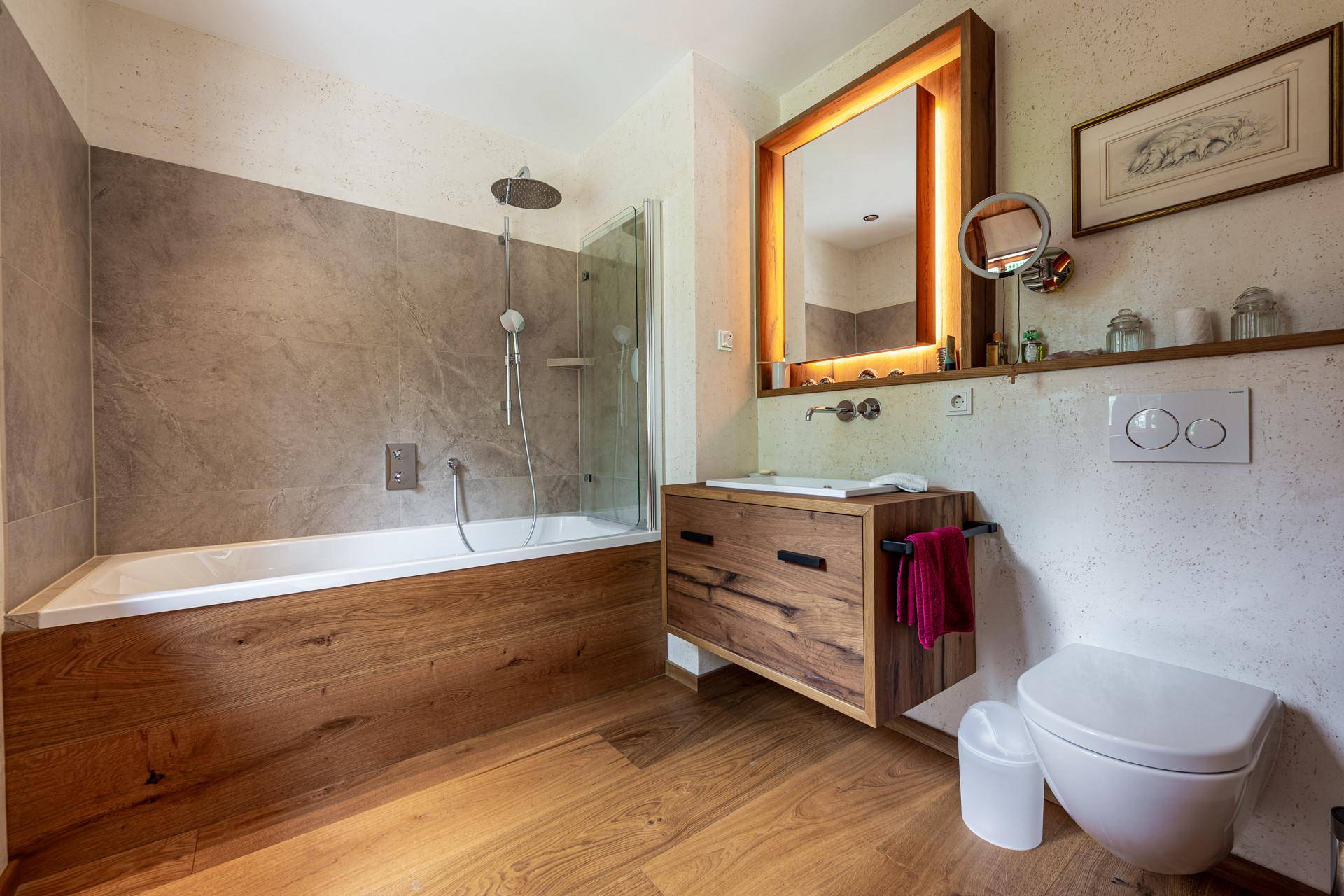 Modernes Badezimmer mit Badewanne, Dusche, Holzwaschtisch und wandhängendem WC, in warmen Farbtönen gehalten.