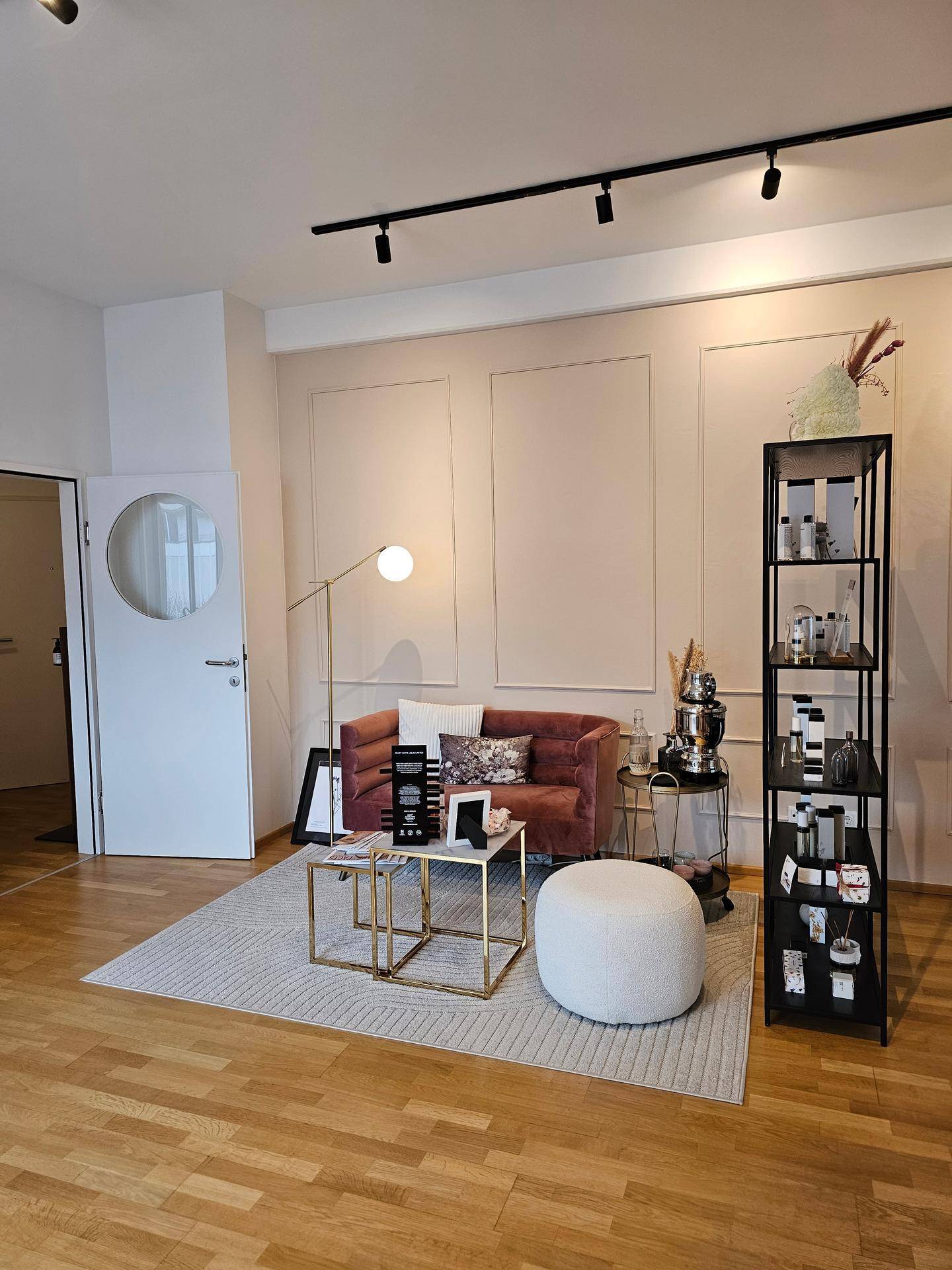 Gemütlicher Wartebereich mit Samtsofa, Couchtischen und dekorativen Elementen auf Holzboden.
