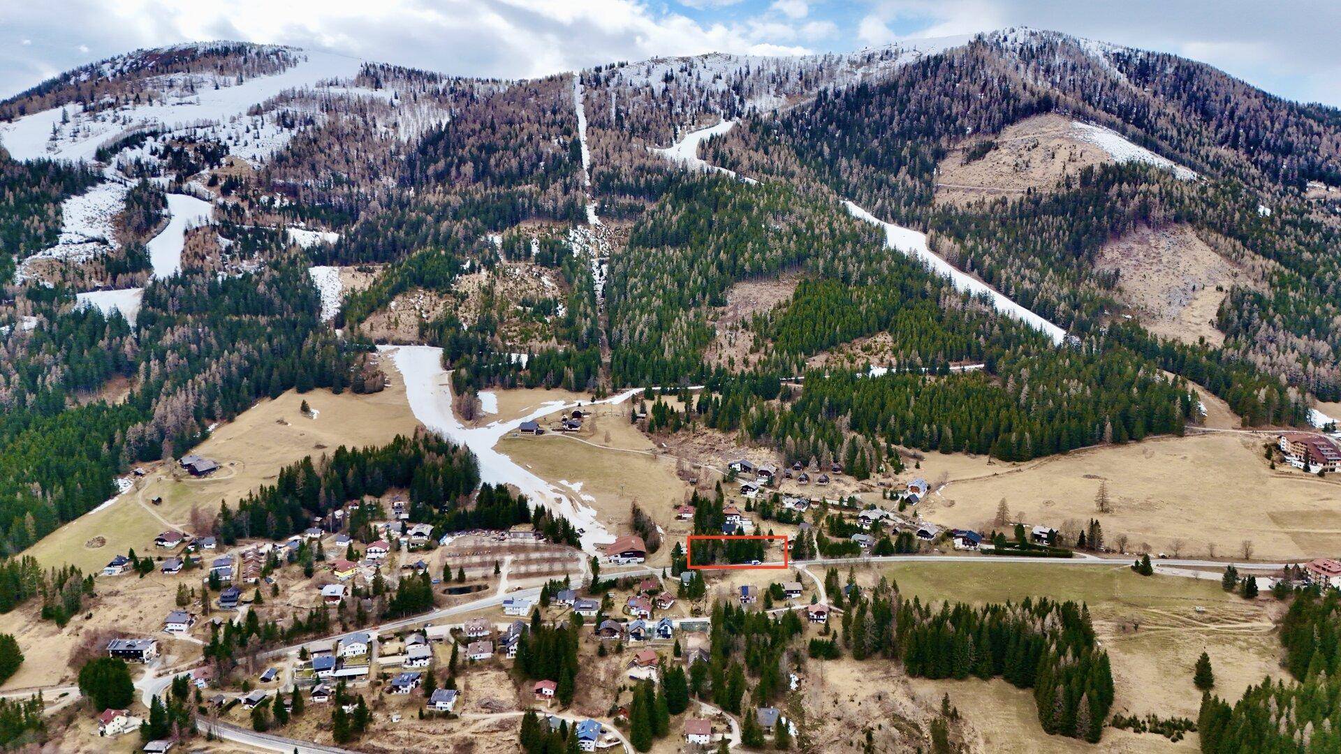 Übersicht aus der Vogelperspektive mit markiertem Grundstück in einer alpinen Dorflandschaft.