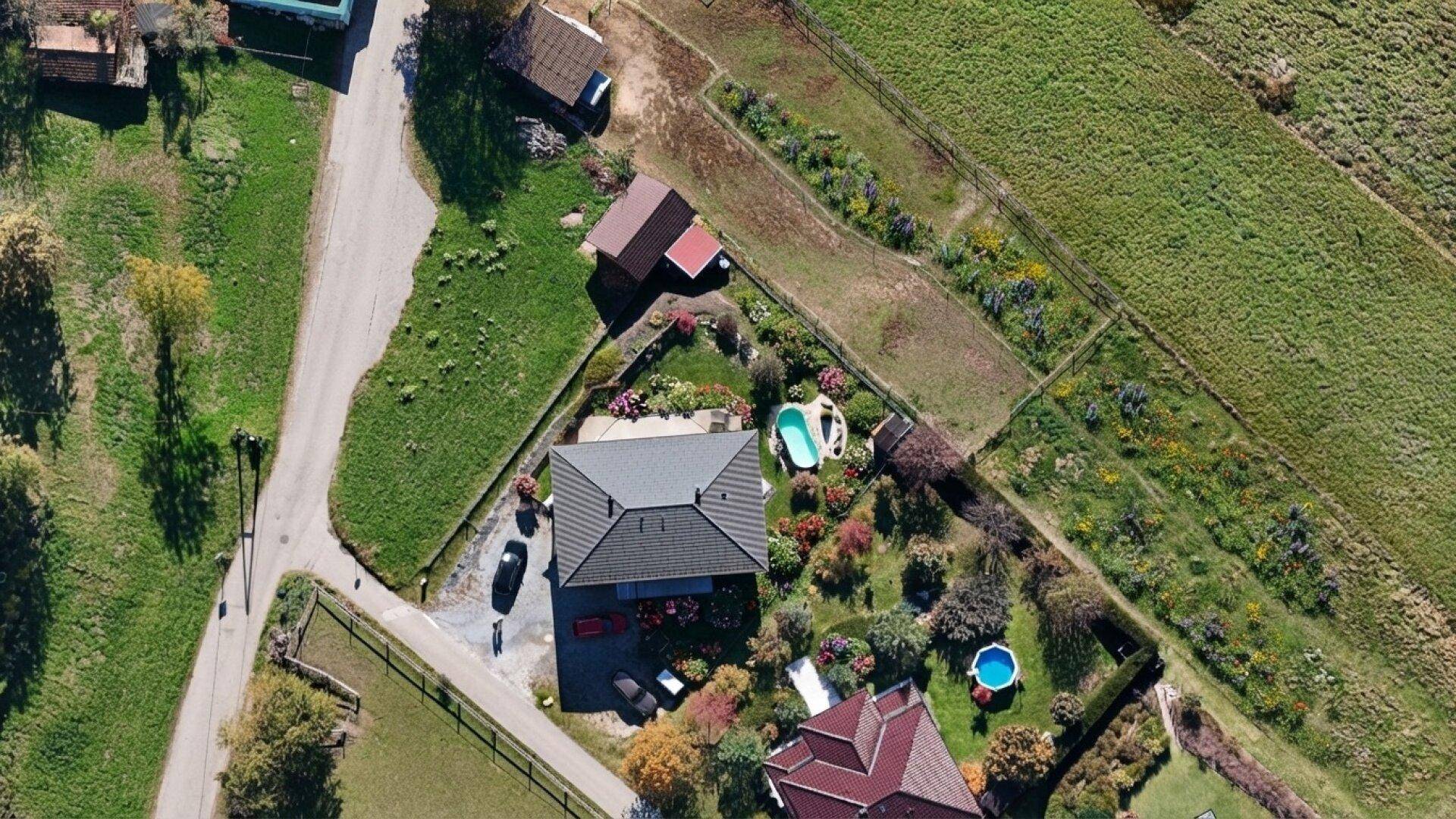 Vogelperspektive des Hauses mit Garten, zwei Pools und angrenzenden Grünflächen.