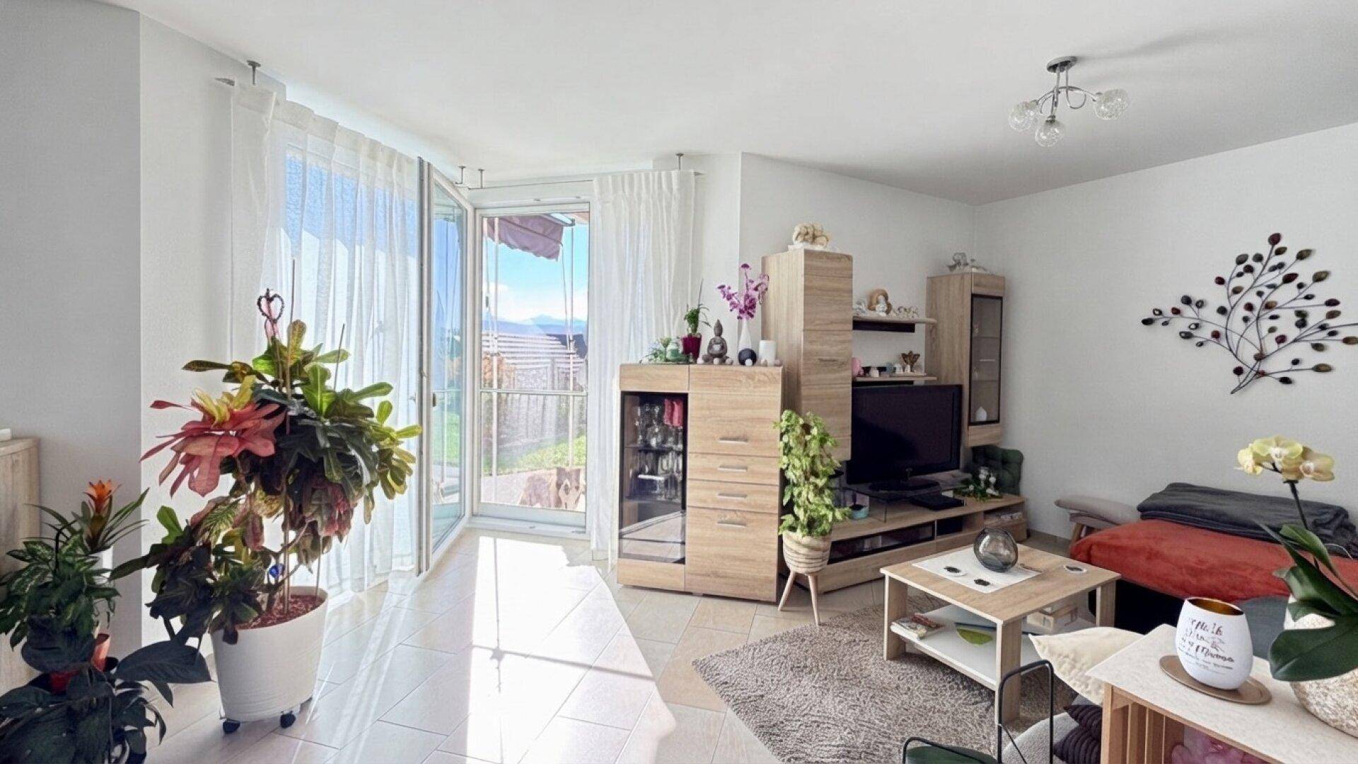 Helles Wohnzimmer mit Fliesenboden, modernen Möbeln und Zugang zur Terrasse.