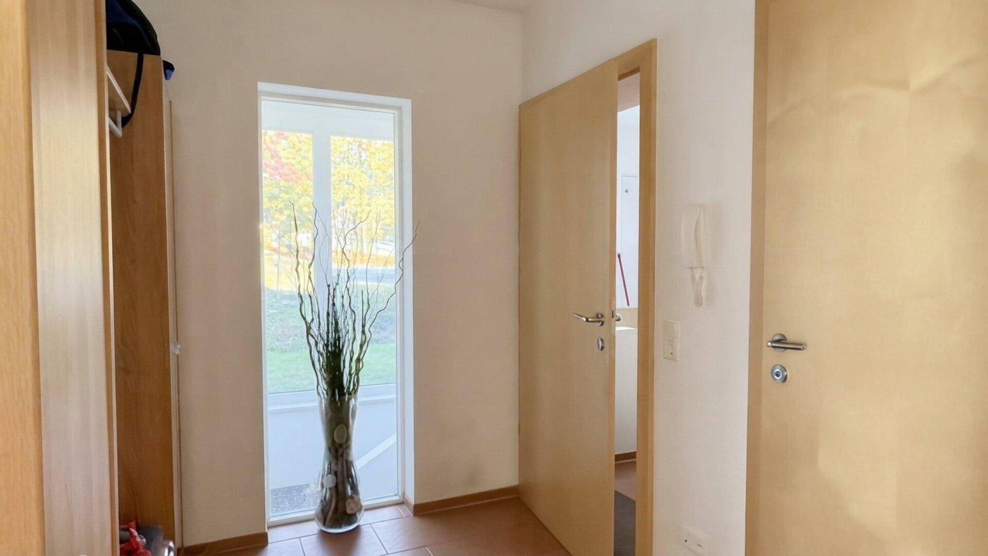 Eingangsbereich mit Fliesenboden, Garderobe und Fenster für natürliches Licht.