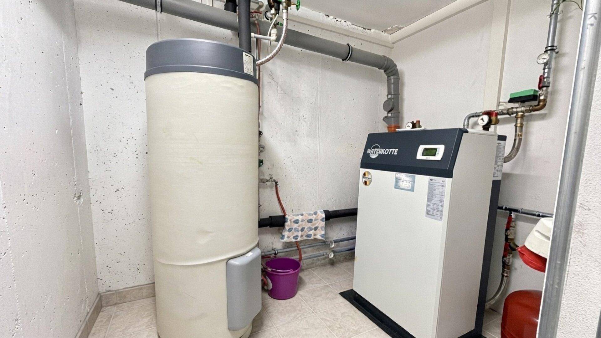 Heizungsraum mit modernem Wärmepumpensystem und Warmwasserspeicher.