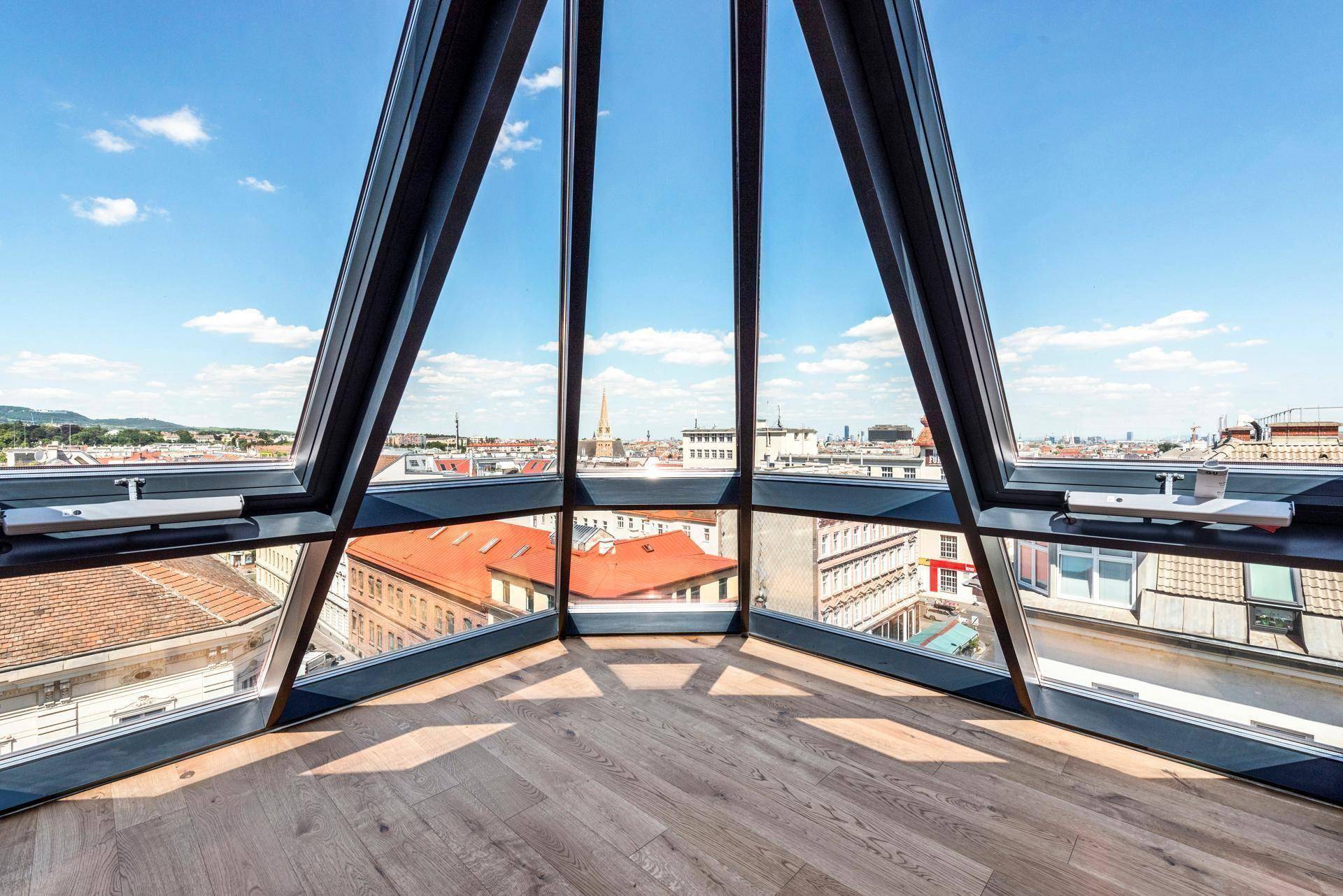 Eckraum mit beeindruckenden Panoramafenstern und Holzboden, der einen weiten Blick über die Stadt ermöglicht.