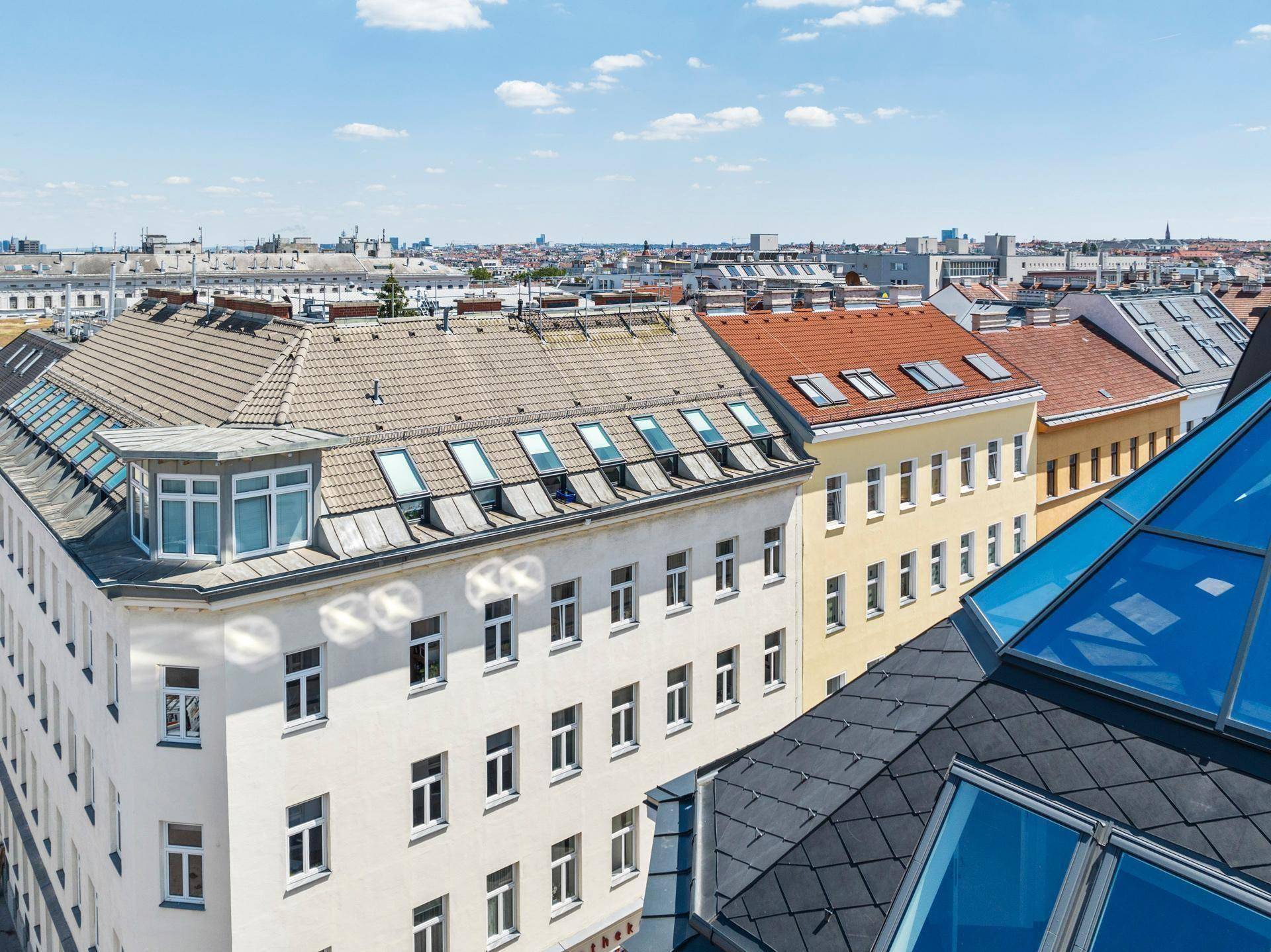 Panoramablick über die Dächer der Stadt mit verschiedenen Gebäuden und einem klaren blauen Himmel.