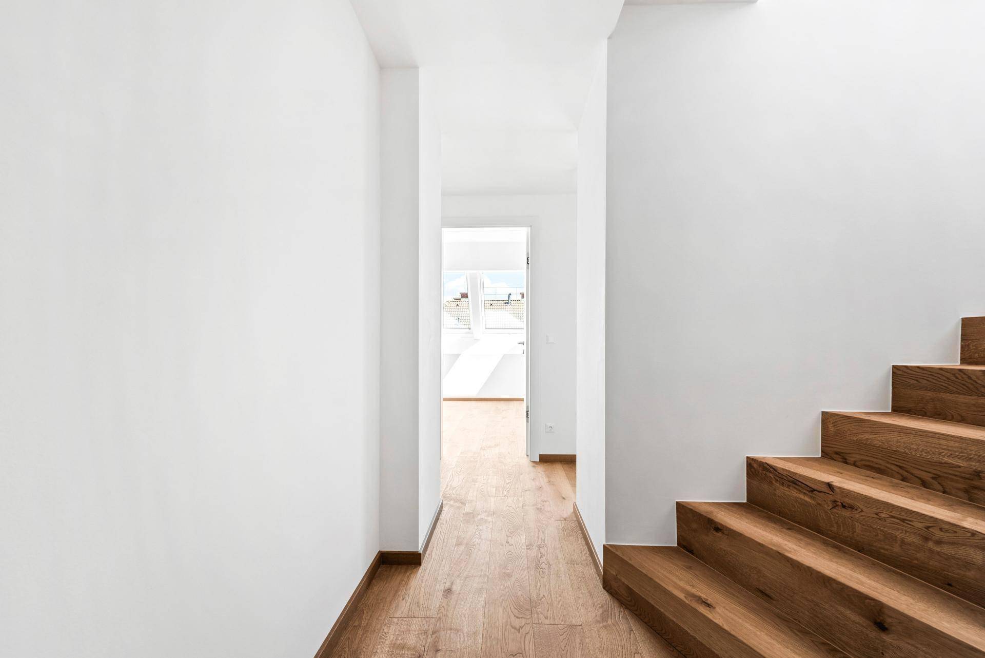 Schlichter Flur mit Holzboden und einer Holztreppe, die in die obere Etage führt.