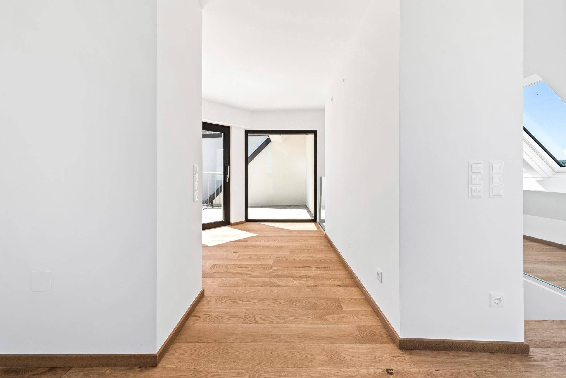 Heller Flur mit Holzboden und Zugang zu weiteren Räumen, durch große Fenster lichtdurchflutet.