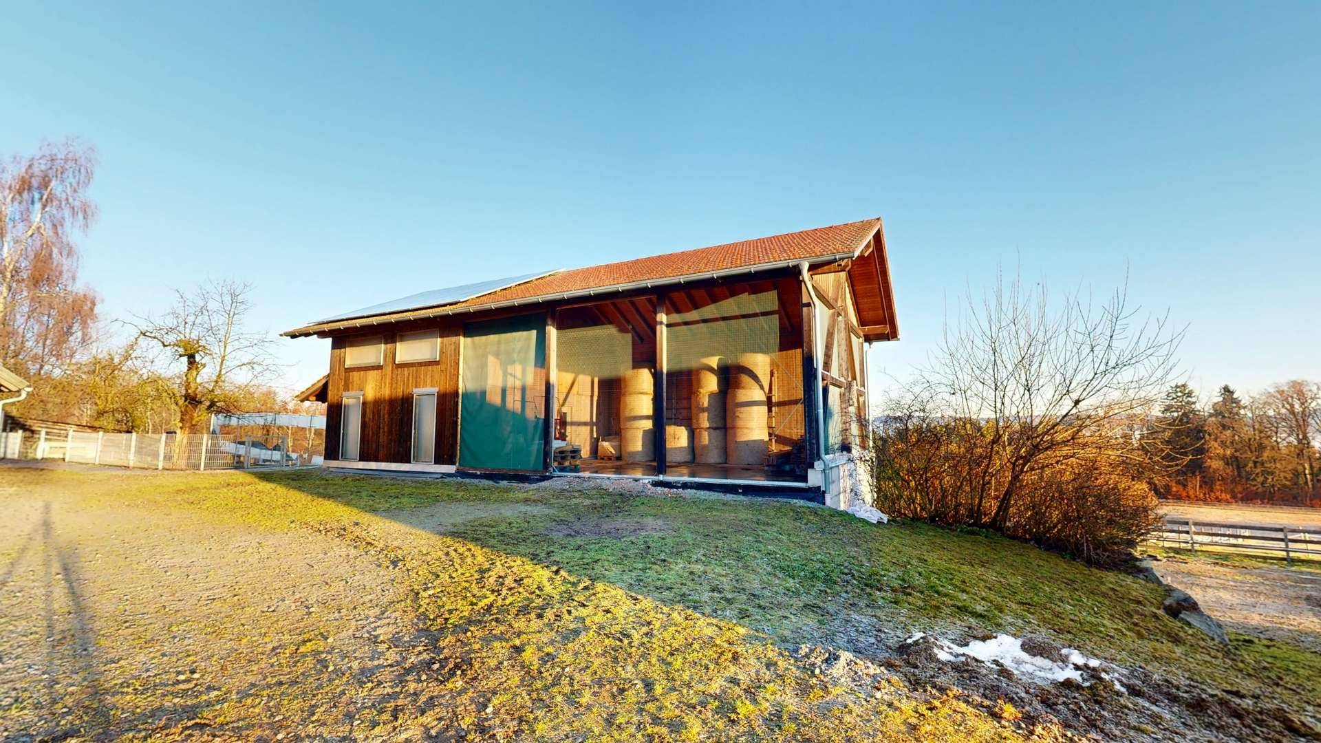 Modernes Scheunengebäude mit Holzfassade und Solarpaneelen auf dem Dach.