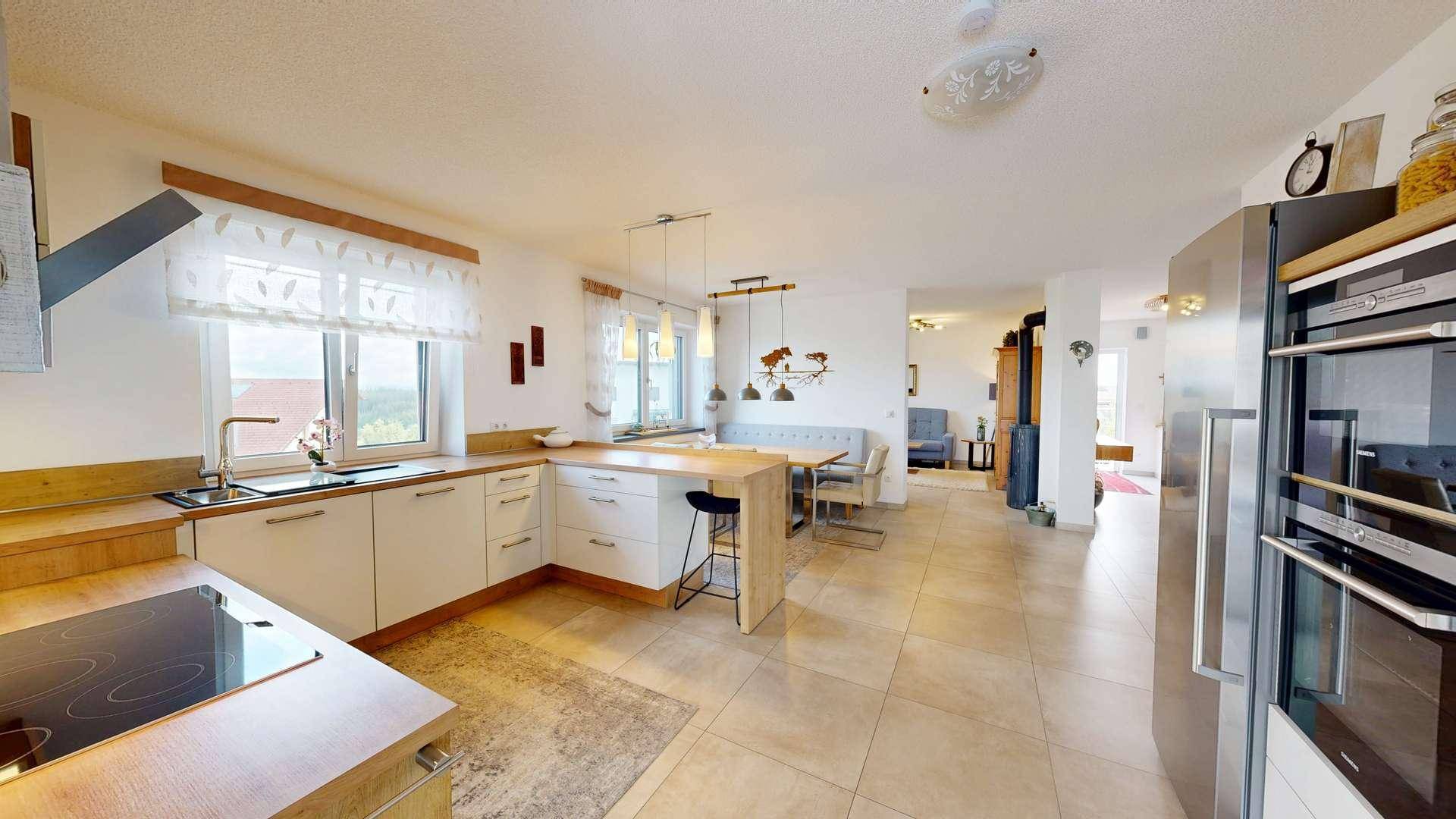 Geräumige offene Küche mit modernen Geräten, Essbereich und Blick in den angrenzenden Wohnbereich.
