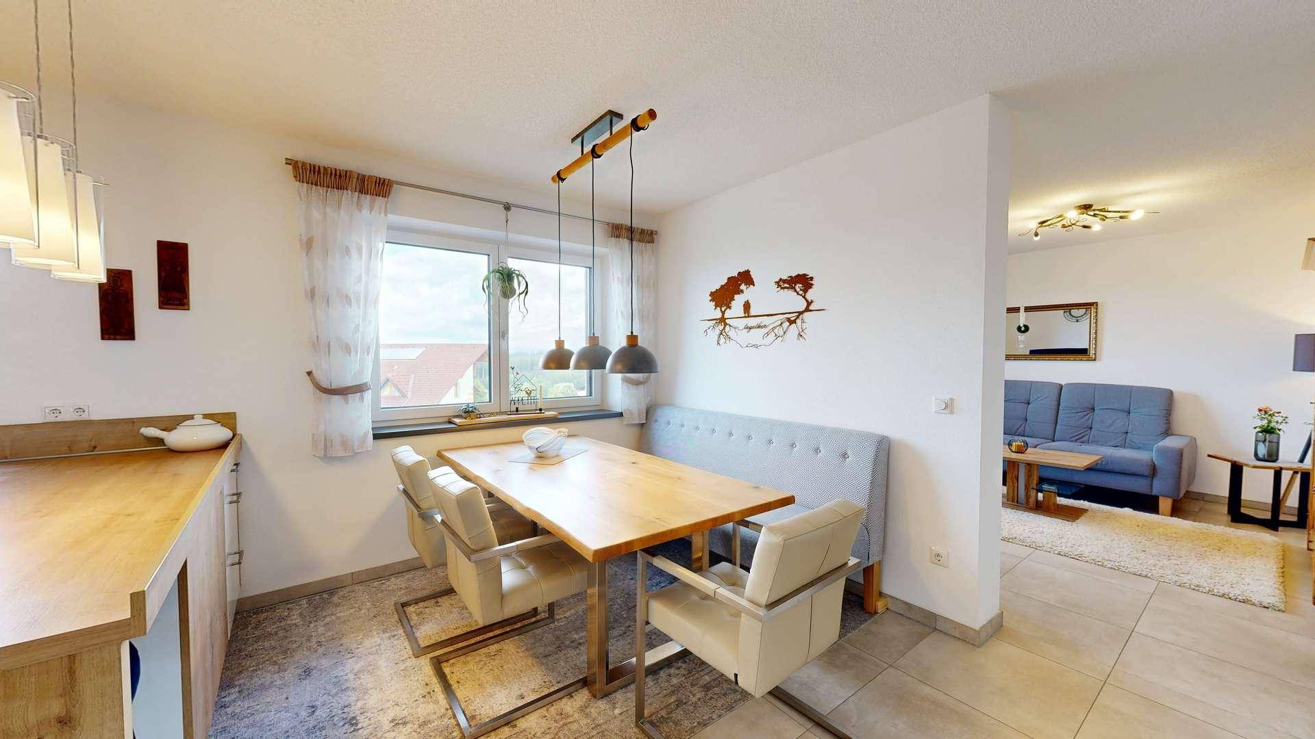 Gemütlicher Essbereich mit Holztisch und Sitzbank, angrenzend an die Küche und mit Blick ins Wohnzimmer.