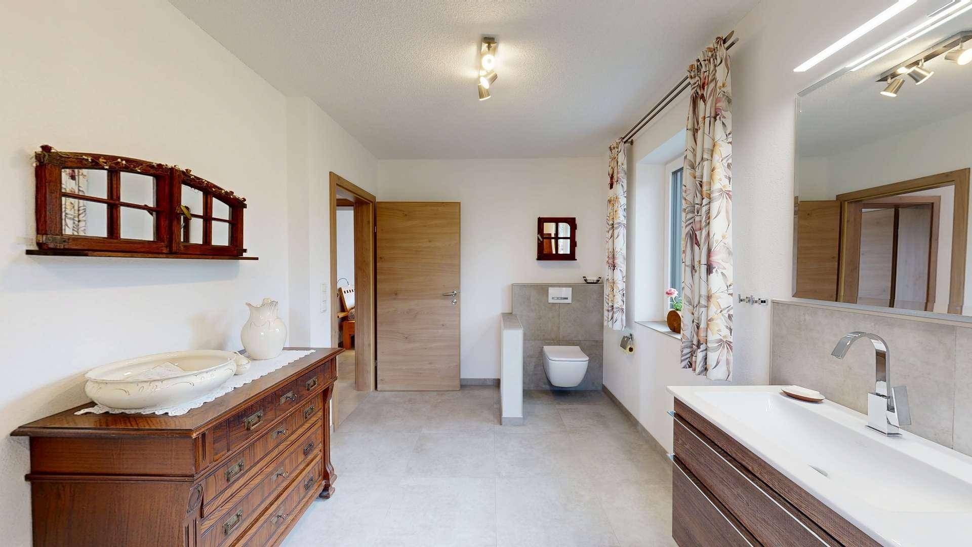 Badezimmer mit Einzelwaschbecken, Wand-WC und einem antiken Holzschrank, kombiniert mit modernen Fliesen.