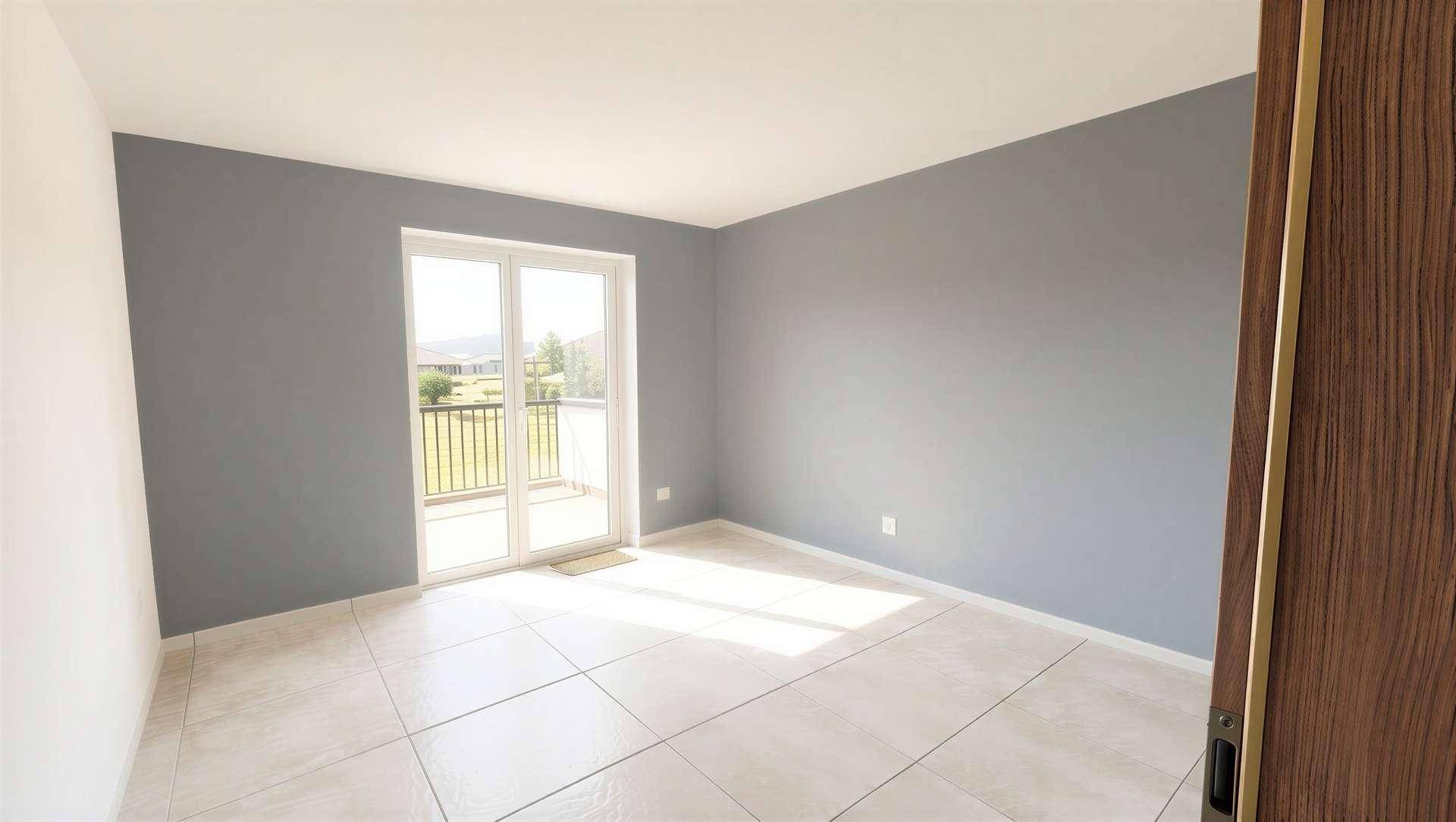 Leeres Schlafzimmer mit grauen Wänden, Fliesenboden und einer Glastür zu einem französischen Balkon.