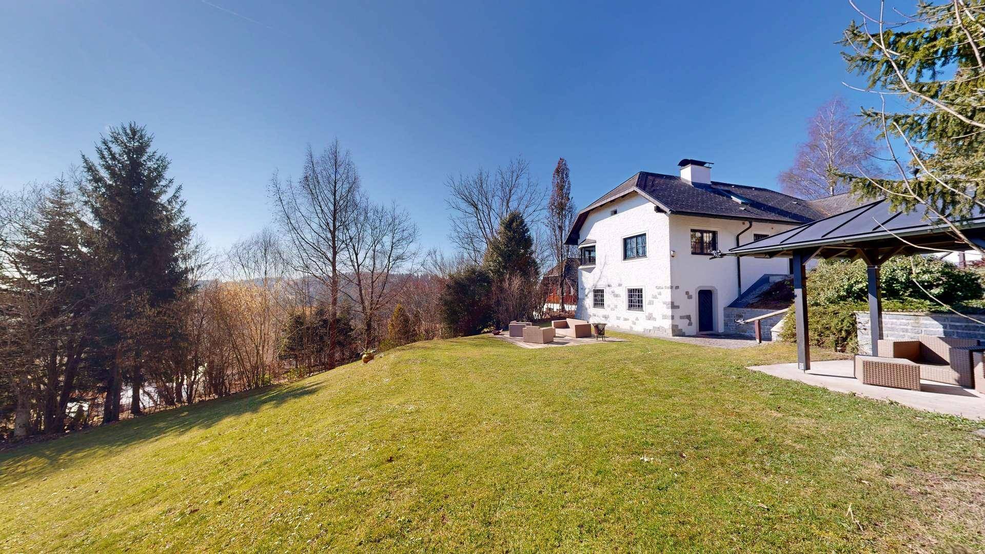 Weitläufiger Gartenbereich mit Rasenfläche, Sitzgelegenheiten und Blick auf die umliegende Landschaft.