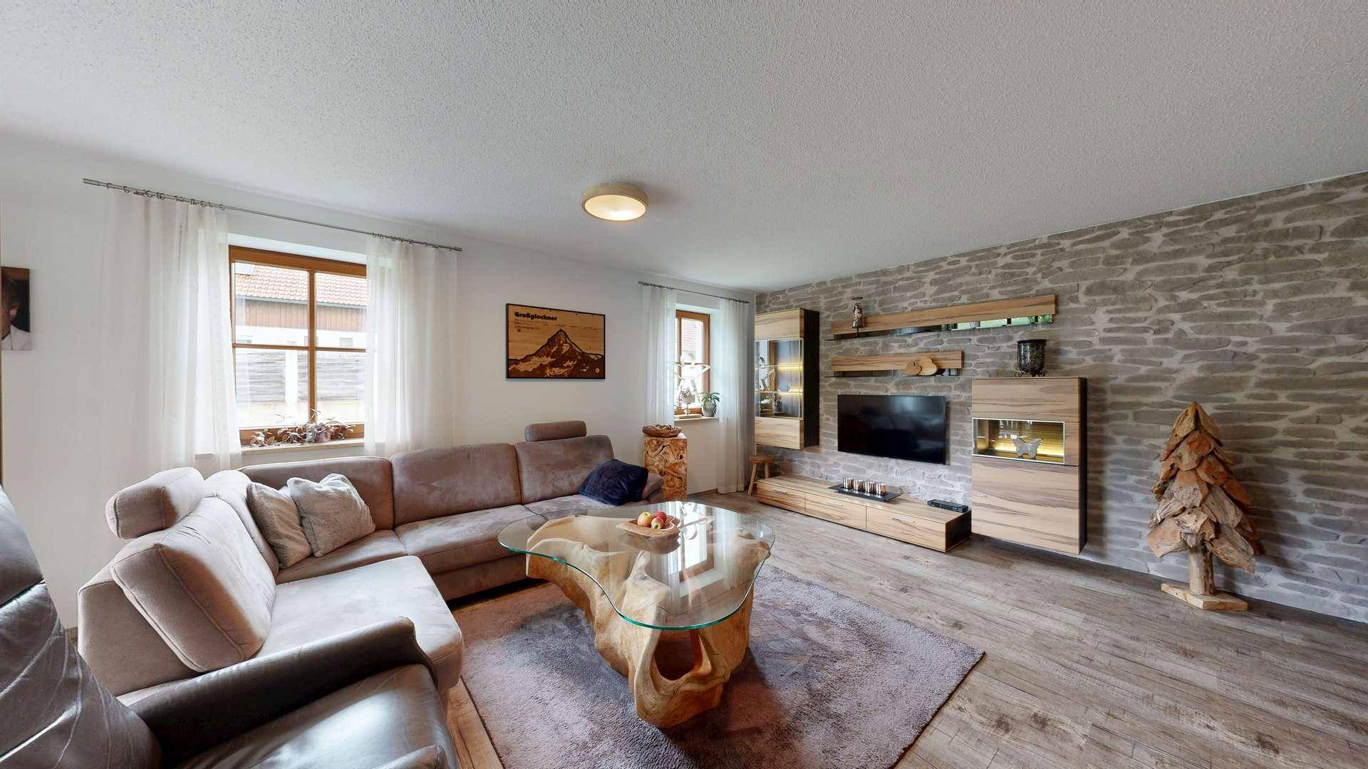 Modernes Wohnzimmer mit Steinwand, großem Ecksofa und Holzelementen.