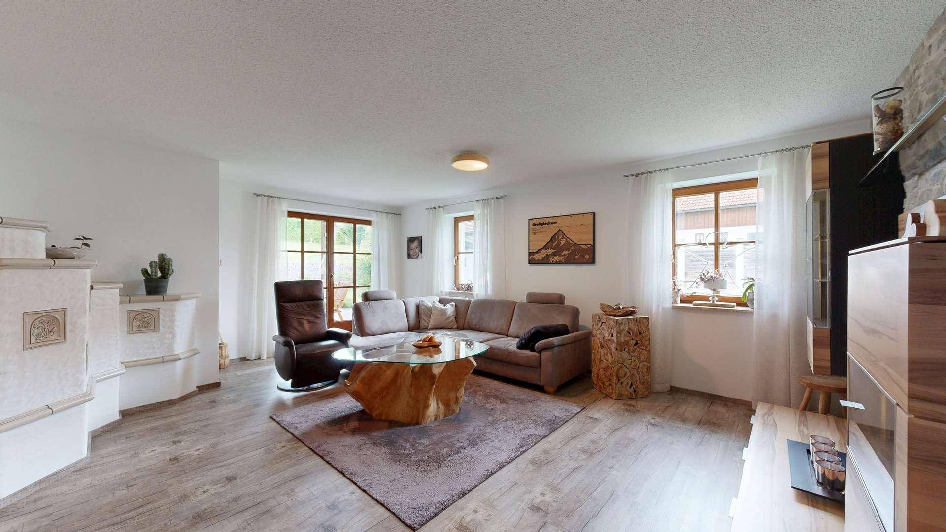 Helles Wohnzimmer mit beigem Sofa, einzigartigem Couchtisch und Kachelofen.
