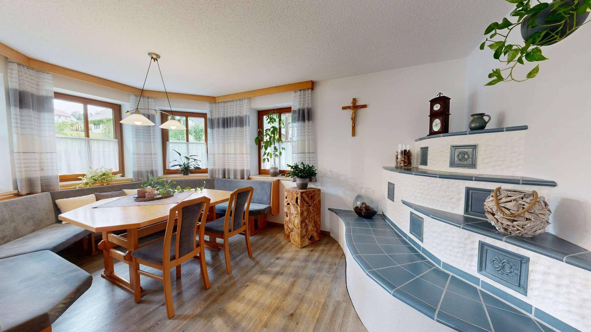 Gemütlicher Essbereich mit traditionellem Kachelofen, Holztisch und Eckbank.