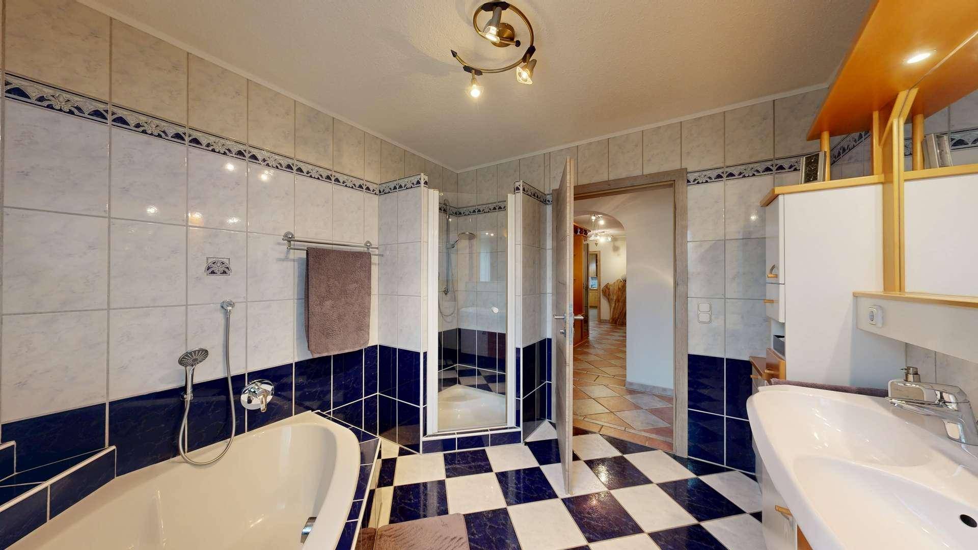 Badezimmer mit blau-weißen Fliesen, Badewanne, Duschkabine und Einzelwaschbecken.