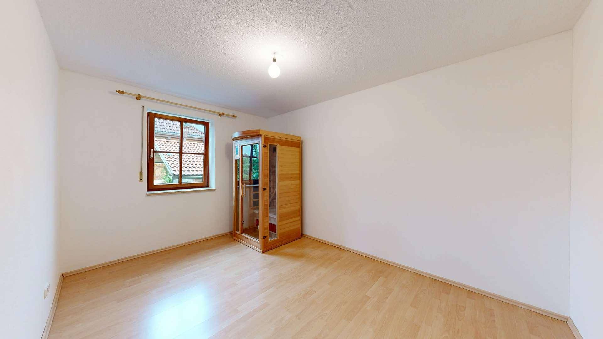 Heller Raum mit einer kleinen Infrarot-Saunakabine und Holzfußboden.