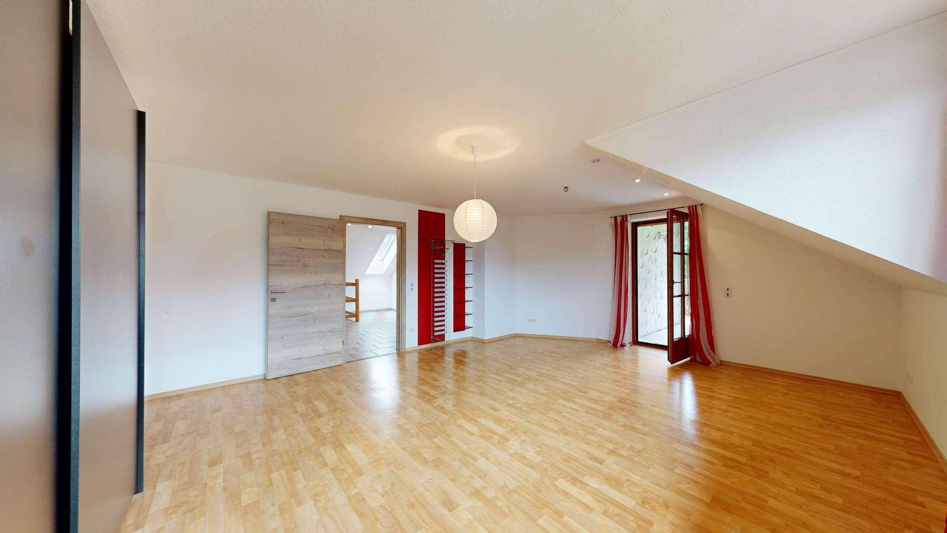 Geräumiges Schlafzimmer mit Holzboden, Dachschräge und Zugang zum Balkon.