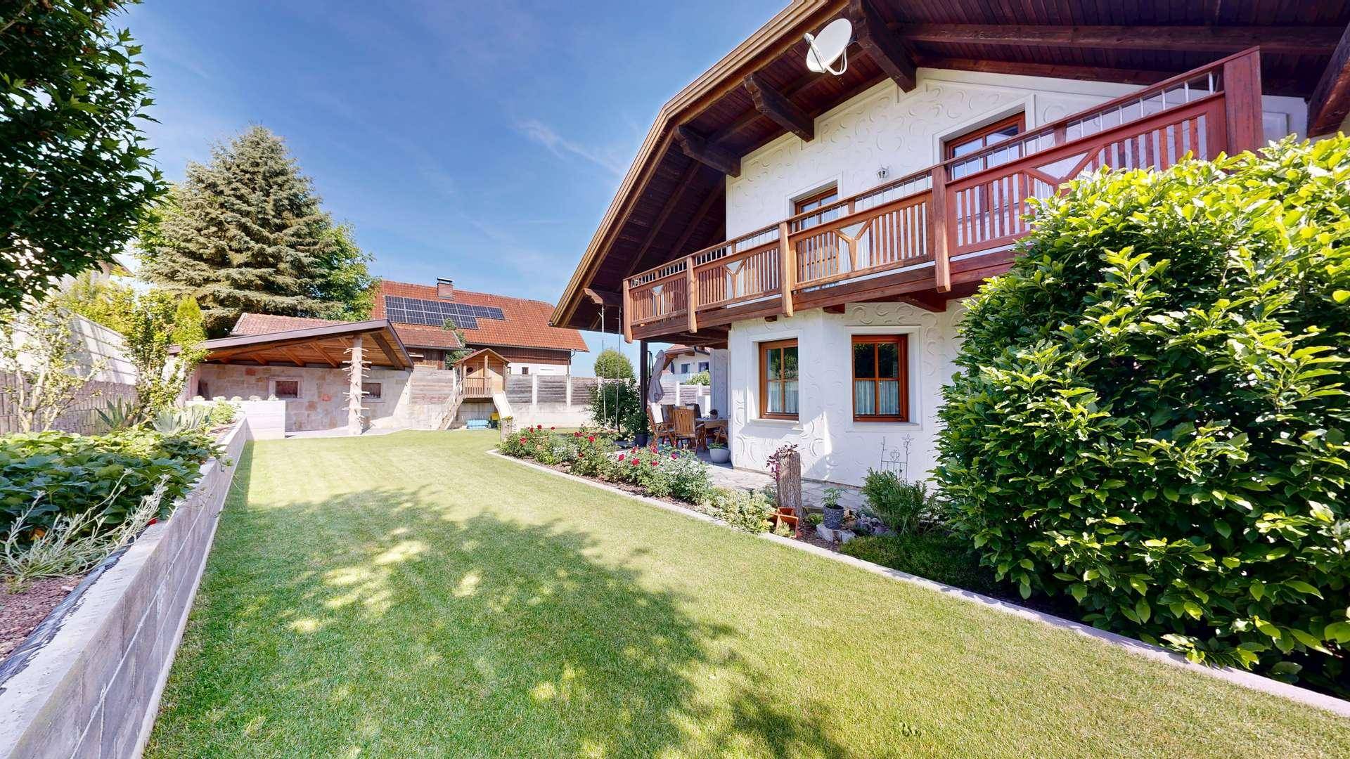 Seitenansicht des Hauses mit gepflegtem Garten, Sträuchern und Gartenhaus im Hintergrund.
