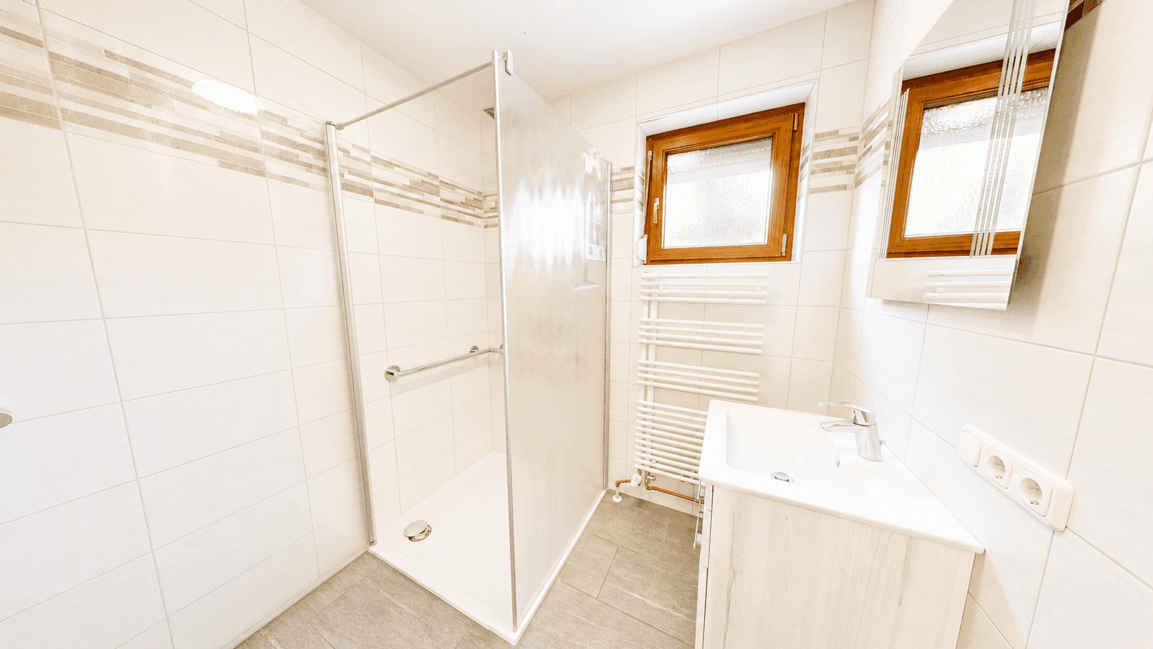 Modernes Badezimmer mit ebenerdiger Dusche, einzelnen Waschbecken und einem Fenster für Tageslicht.
