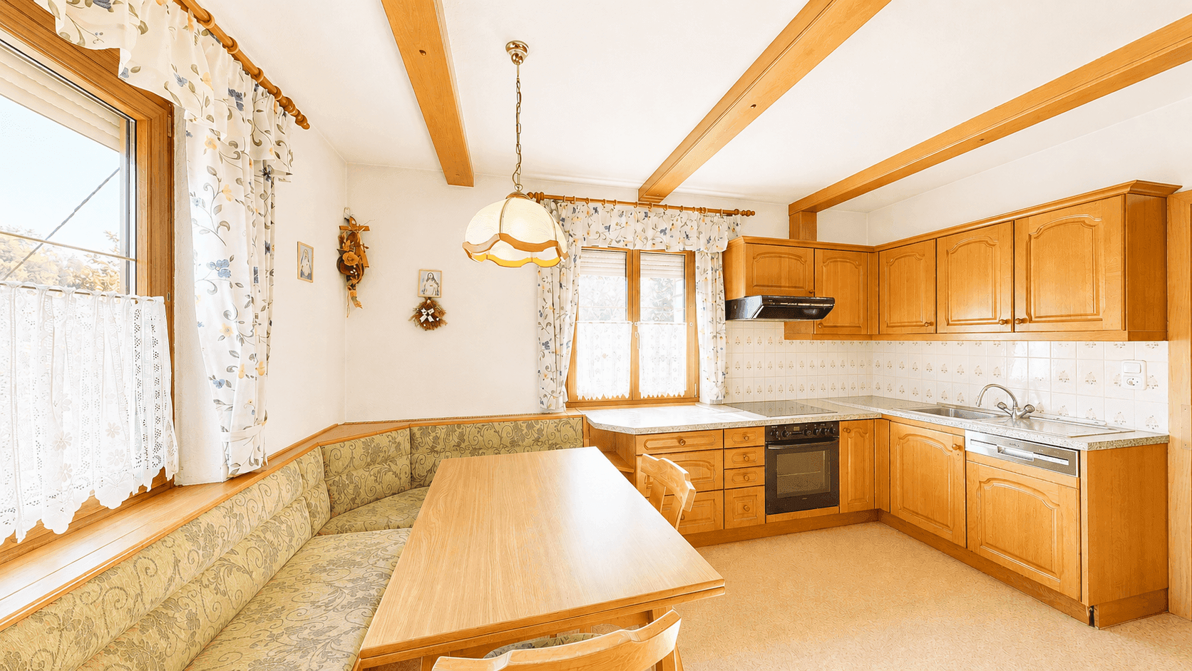 Gemütliche Wohnküche mit Holzeinbauten, Eckbank und sichtbaren Deckenbalken, ideal für Familienessen.