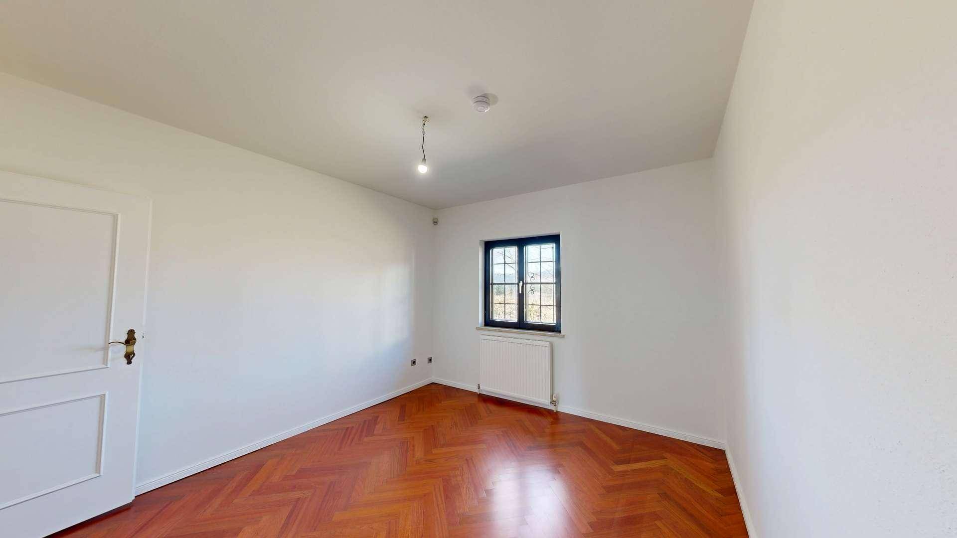 Helles Schlafzimmer mit Fischgrätparkett und einem Fenster, bereit zur individuellen Gestaltung.