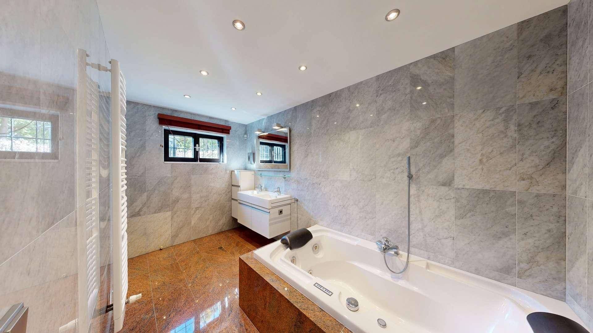 Luxuriöses Badezimmer mit Marmorfliesen, Whirlpool-Badewanne und separater Dusche.