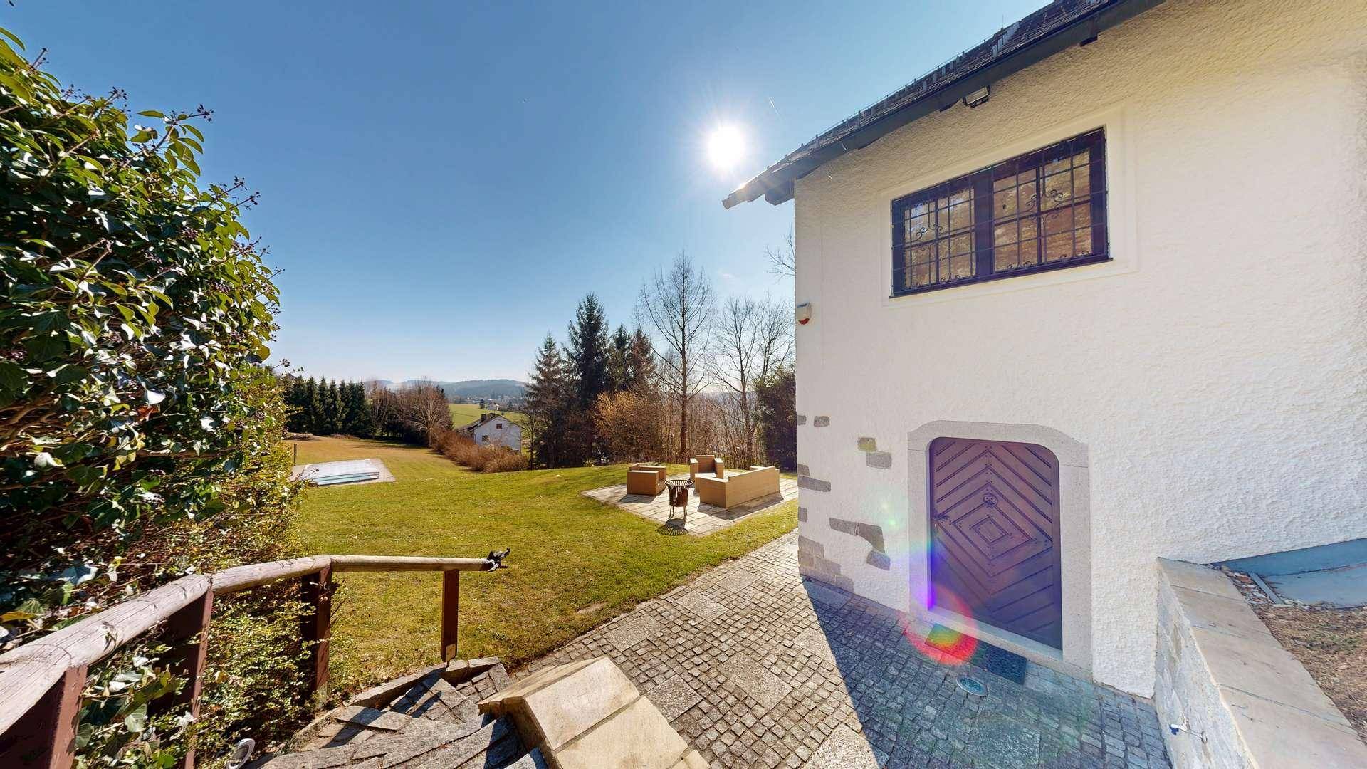 Sonnige Gartenseite des Hauses mit weitläufiger Rasenfläche und gemütlicher Sitzgelegenheit im Freien.