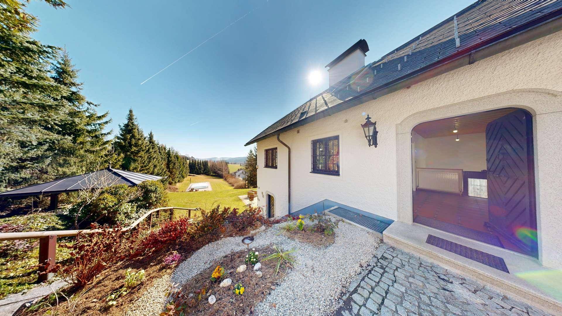 Charmantes Landhaus mit gepflastertem Eingangsbereich und weitem Blick in die grüne Landschaft.