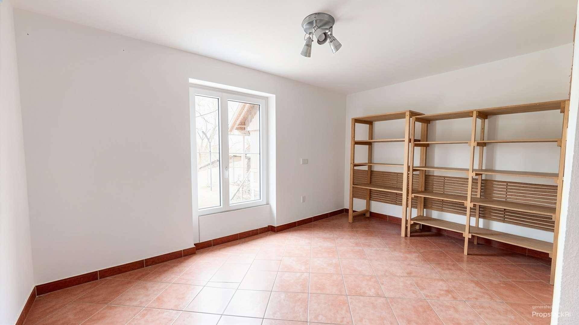 Leerer Raum mit Fliesenboden, weiß gestrichenen Wänden und Holzregalen.