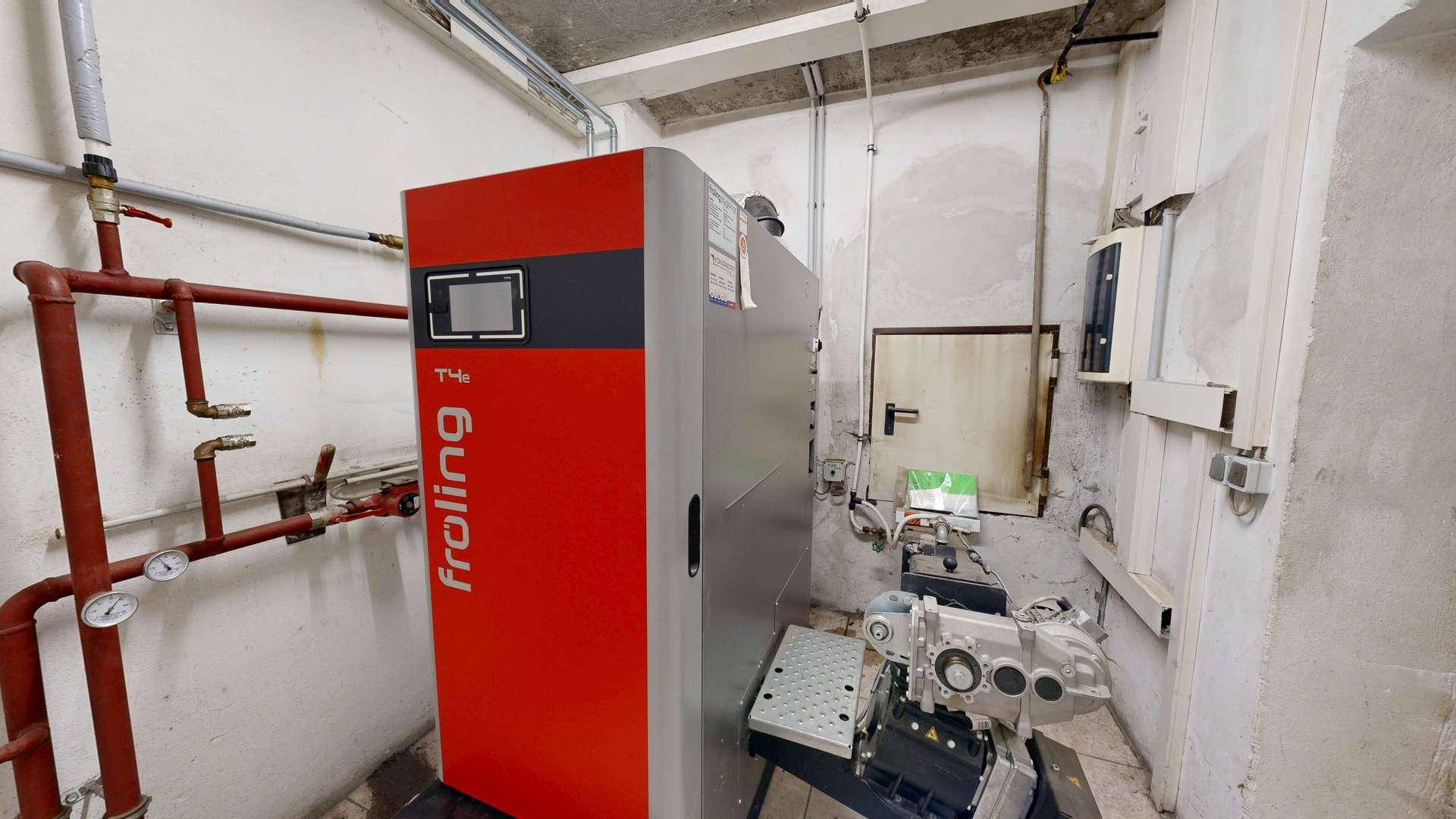 Heizungsraum mit moderner Froling-Heizanlage und sichtbaren Rohrleitungen, funktional gestaltet.