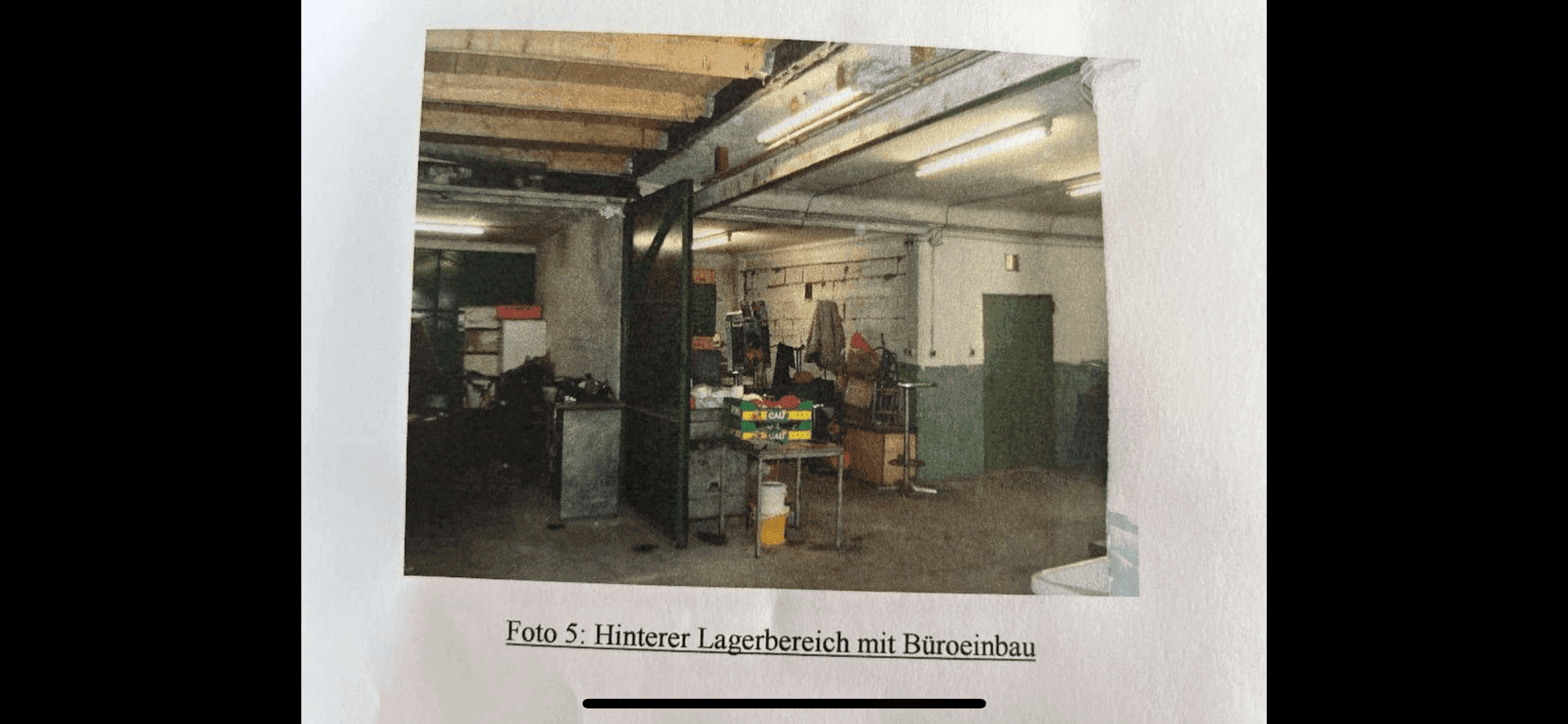 Foto eines hinteren Lagerbereichs mit verschiedenen Gegenständen, Rohren und einem einfachen Büroausbau.