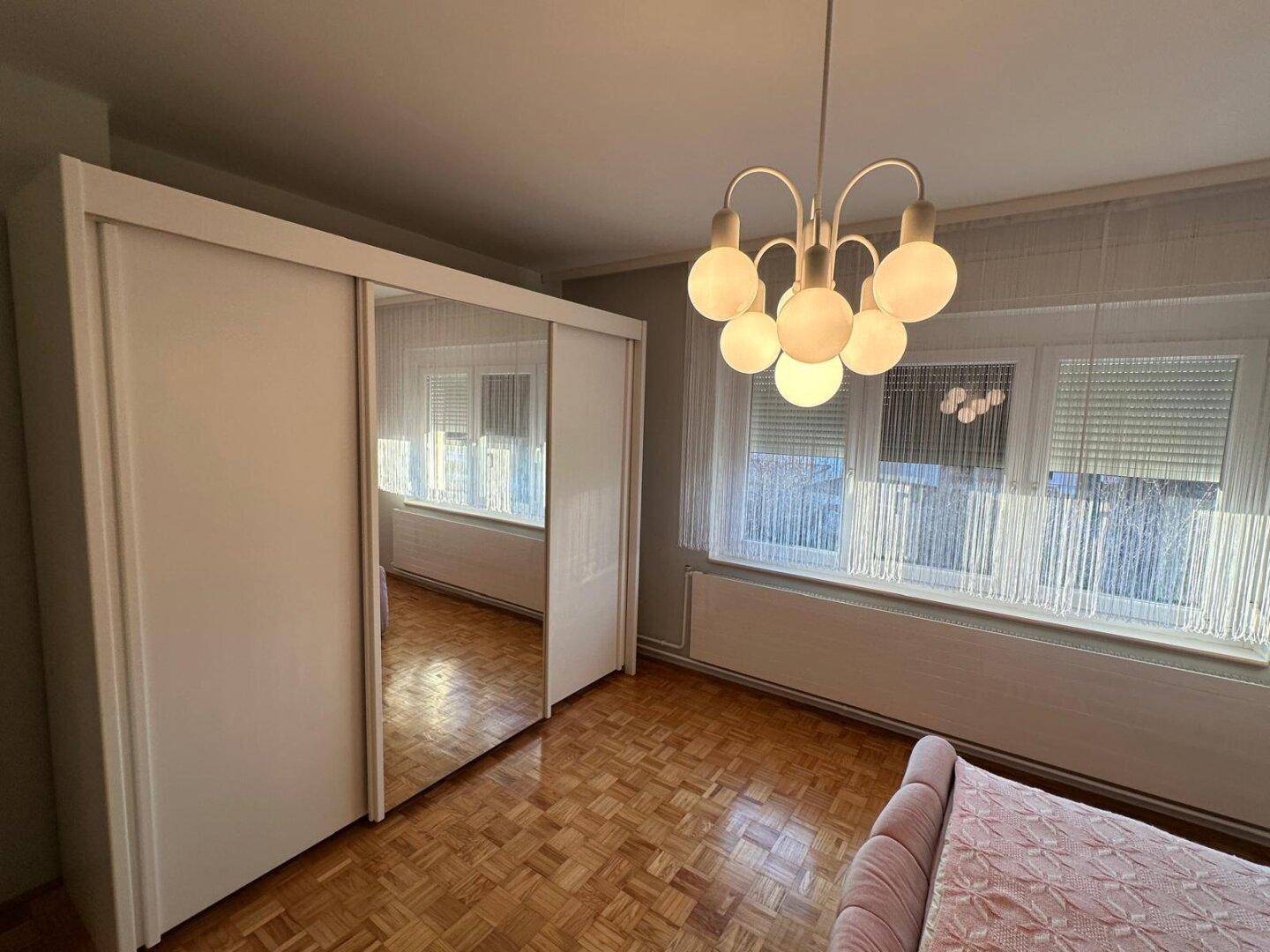 Schlafzimmer mit einem großen Spiegelschrank und klassischem Parkettboden.