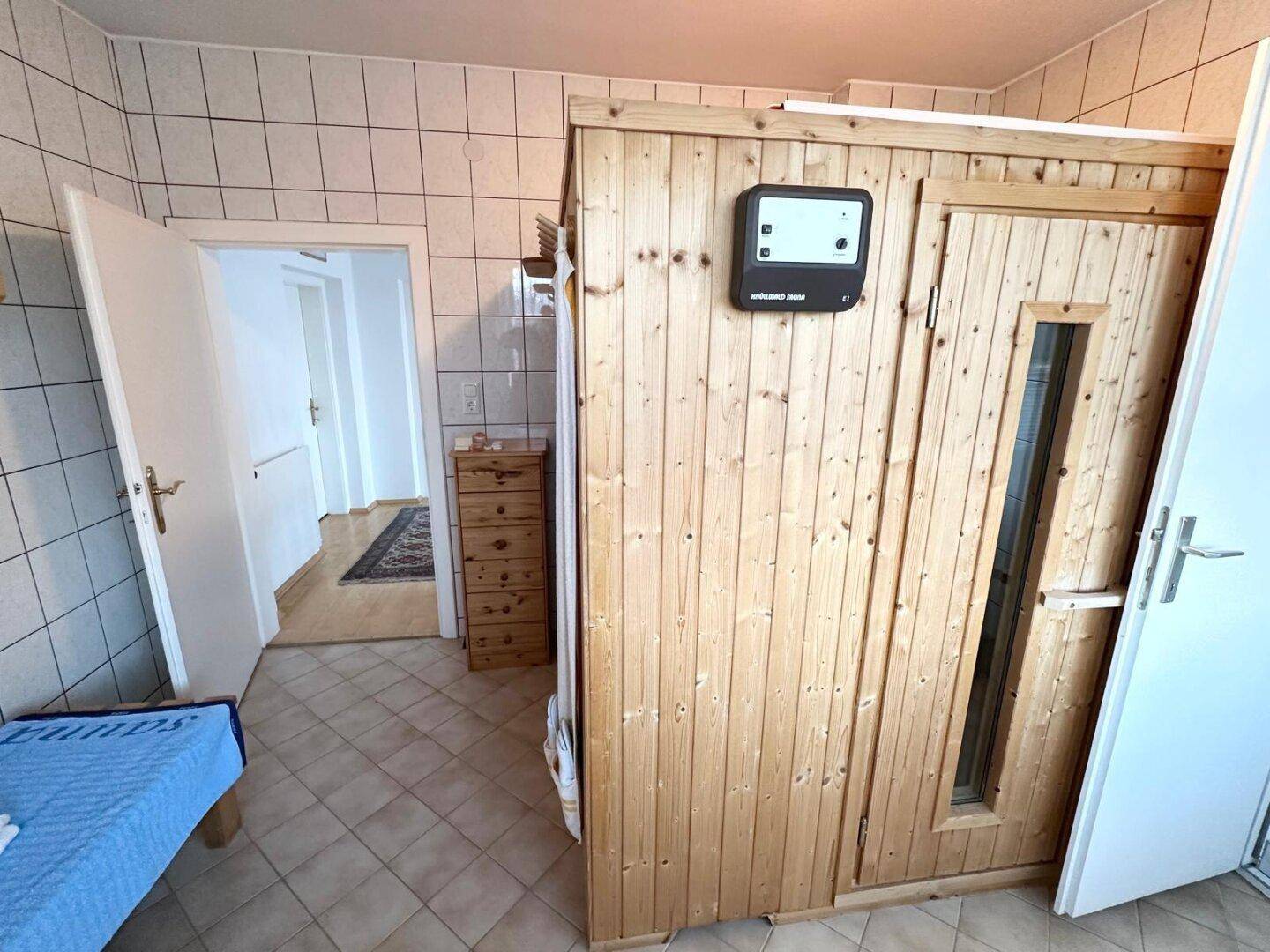 Raum mit Saunakabine und Zugang zu einem weiteren Zimmer.