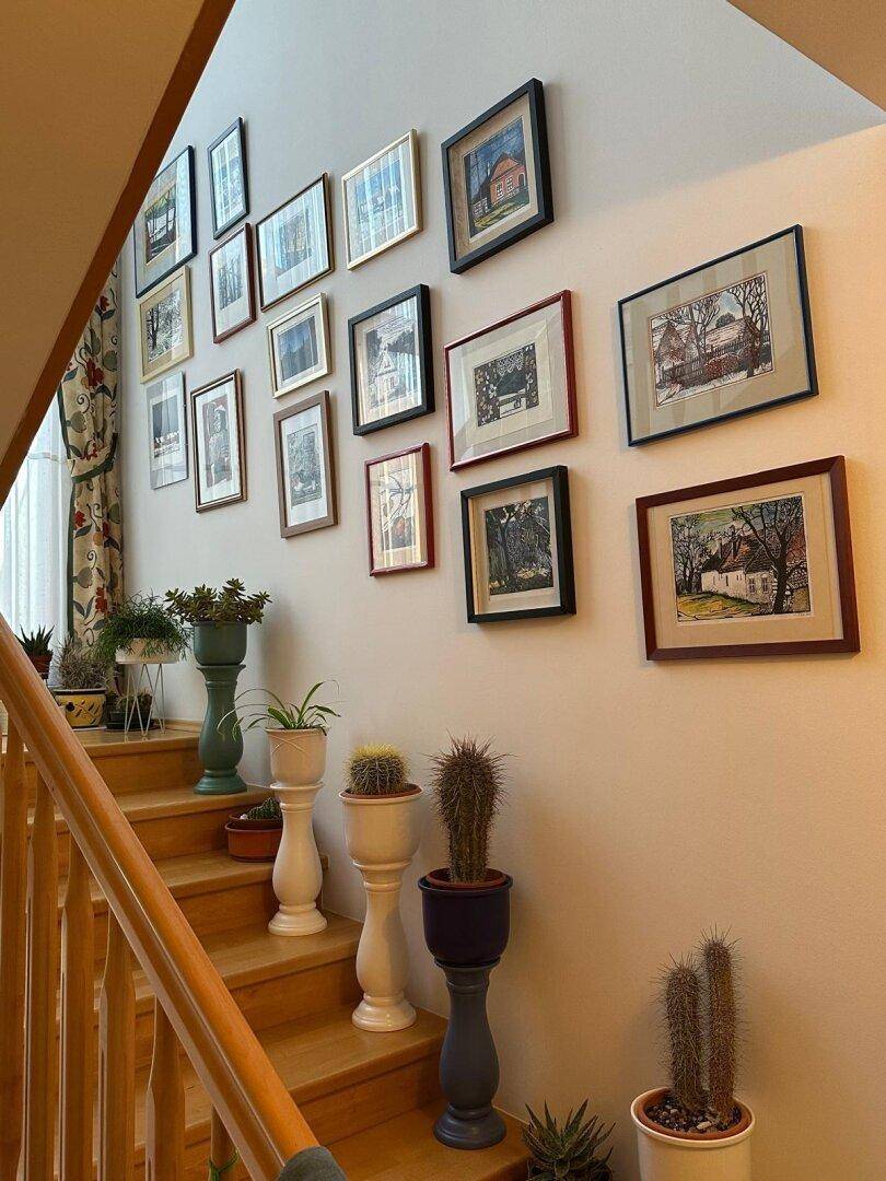 Treppenhaus mit Holzstufen und einer Wanddekoration aus gerahmten Bildern.