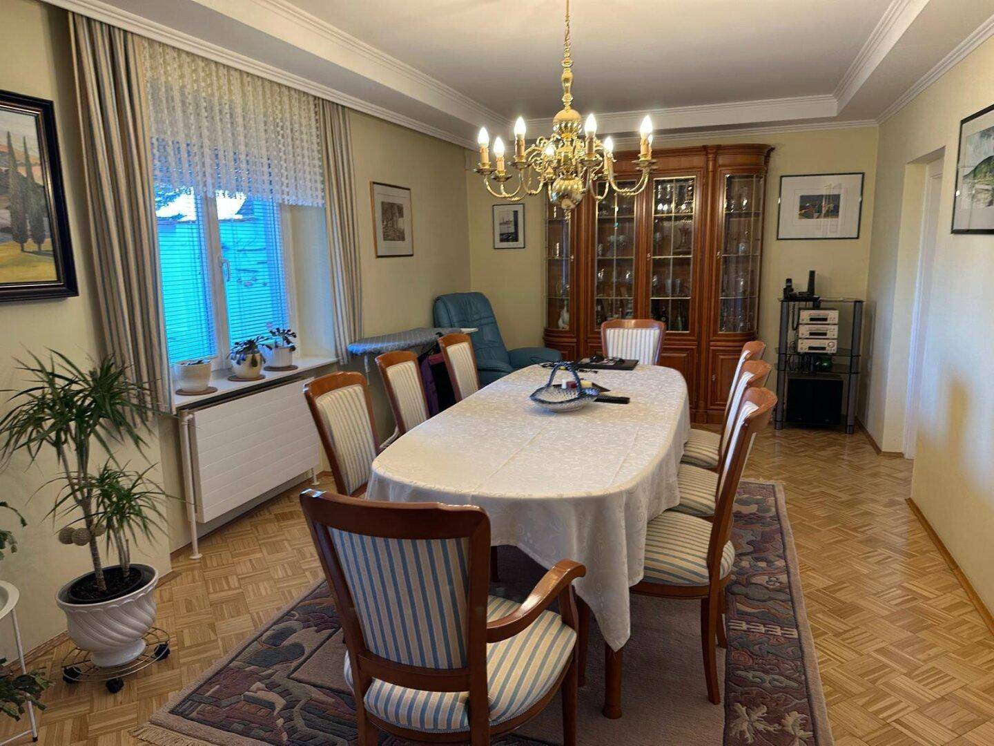 Klassisches Esszimmer mit großem Esstisch, Holzschrank und Fischgrätparkettboden.
