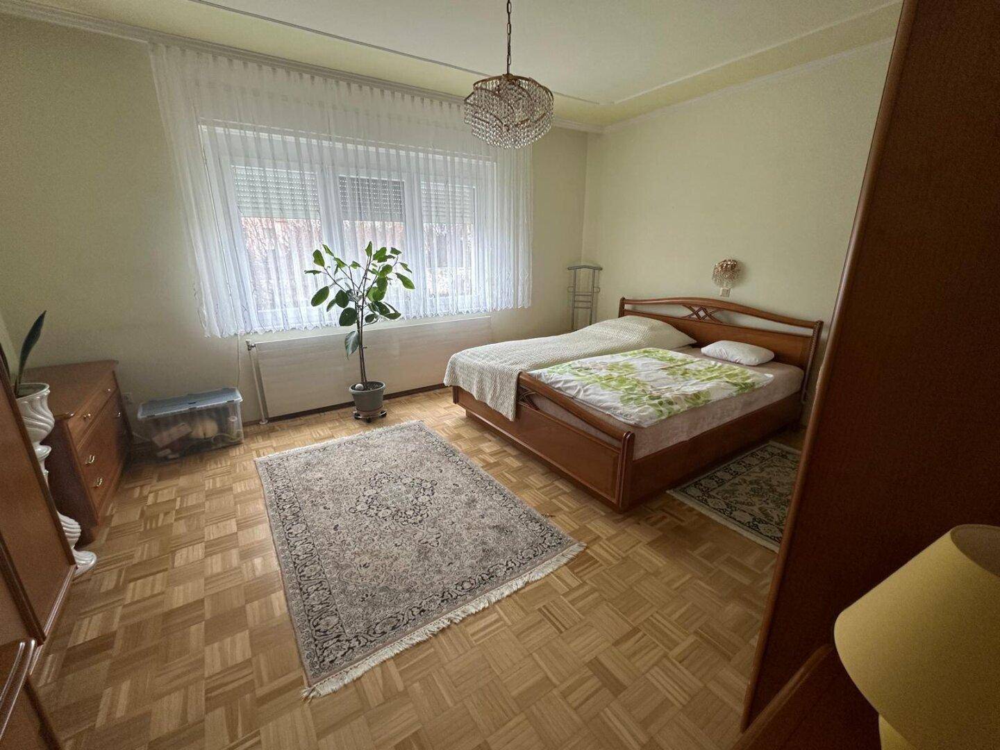 Schlafzimmer mit zwei Einzelbetten, Holzmöbeln und Parkettboden.