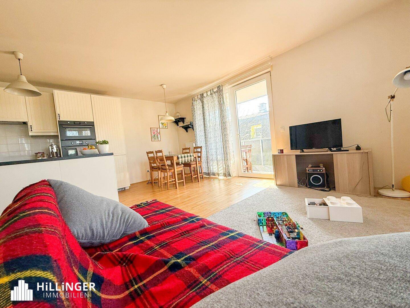 Heller Wohnbereich mit offener Küche, Essplatz und direktem Zugang zum sonnigen Balkon.