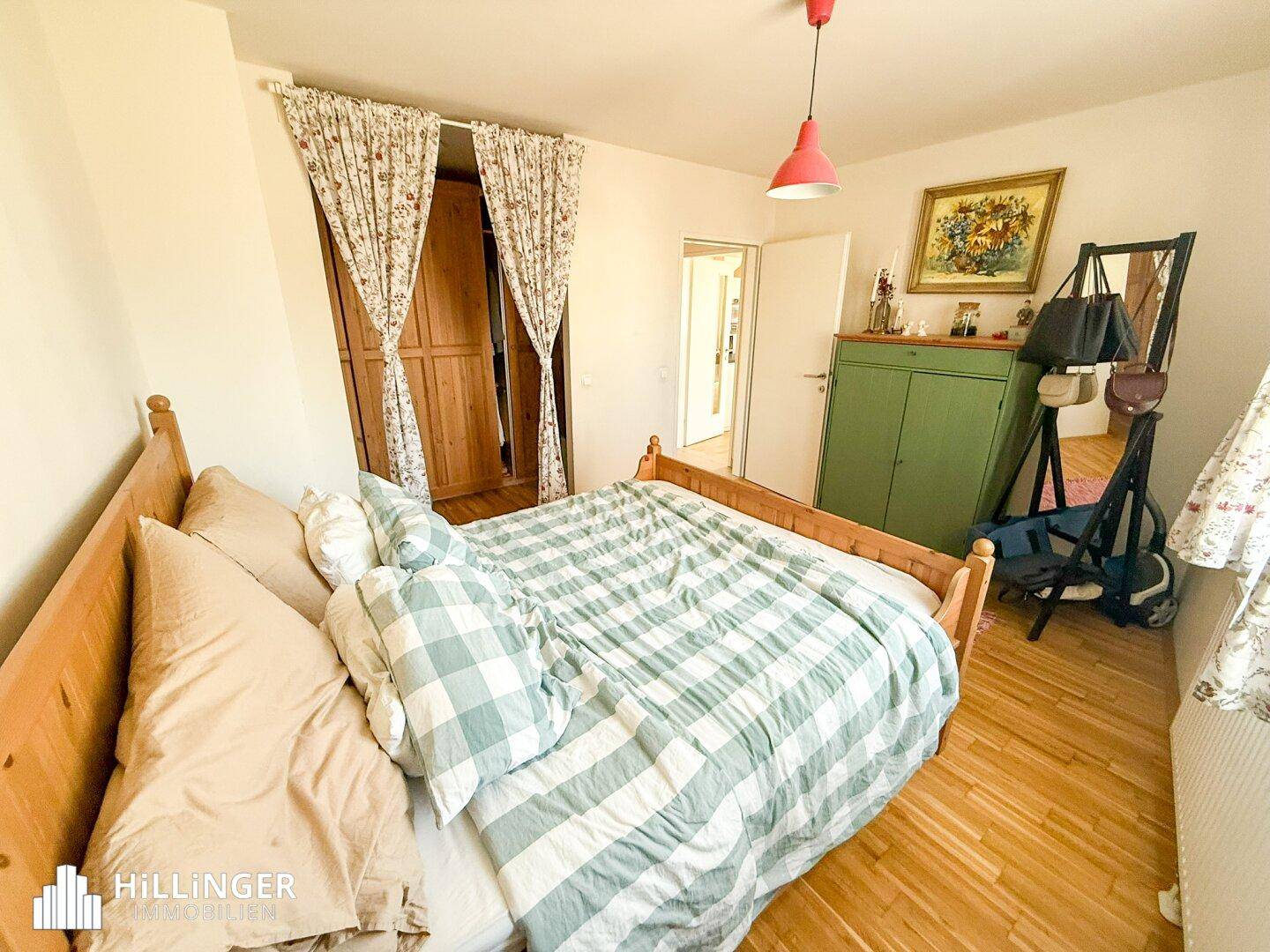 Helles Schlafzimmer mit Holzbett, Kleiderschrank und Fenster, das eine angenehme Atmosphäre schafft.
