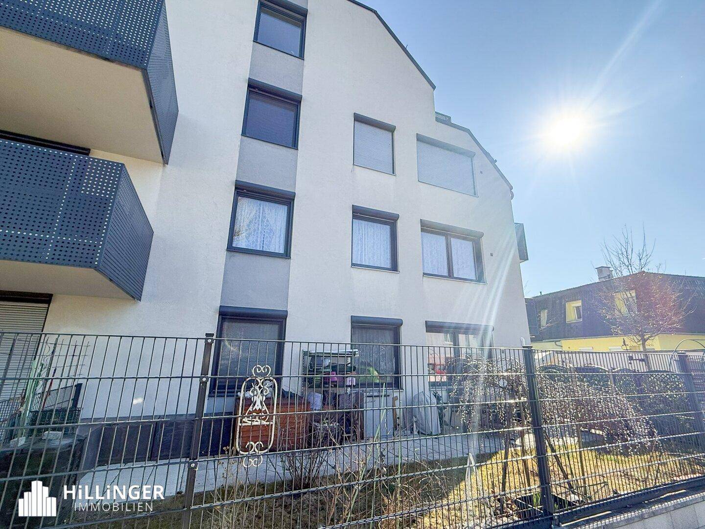 Fassade des modernen Wohnhauses mit großen Fenstern und Terrassen im Erdgeschoss.