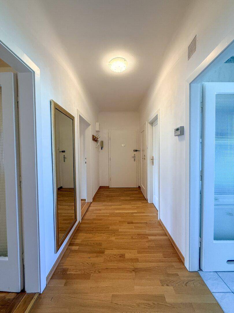 Heller Flur mit Parkettboden und mehreren Türen, der zu verschiedenen Räumen führt.