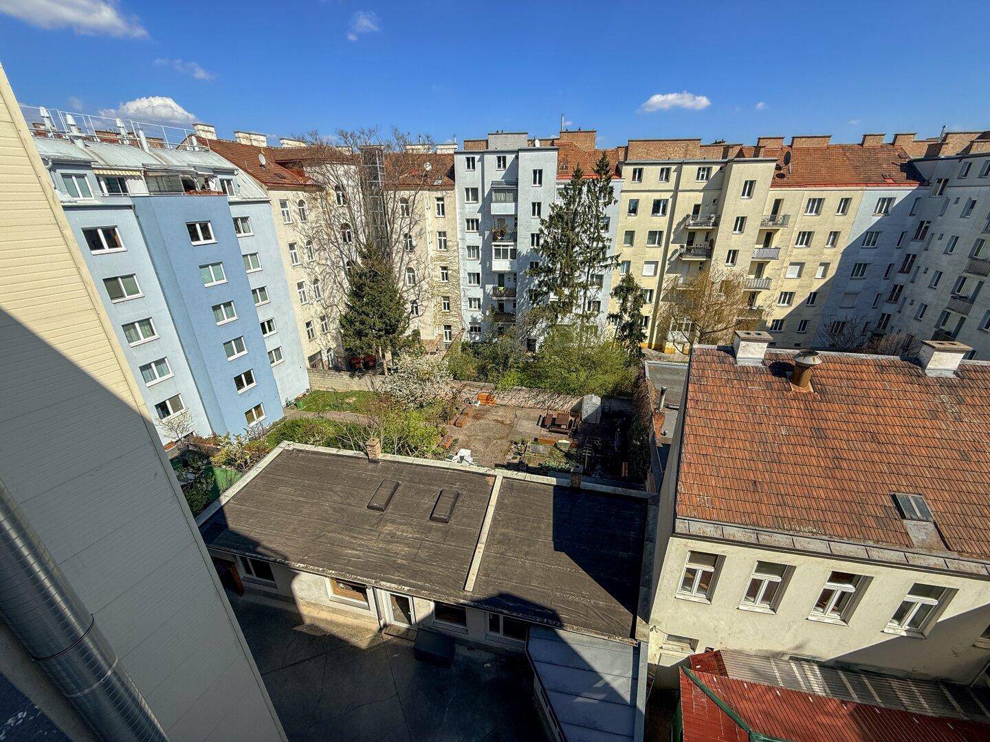 Blick auf einen Innenhof mit mehreren Gebäuden und etwas Grünfläche.