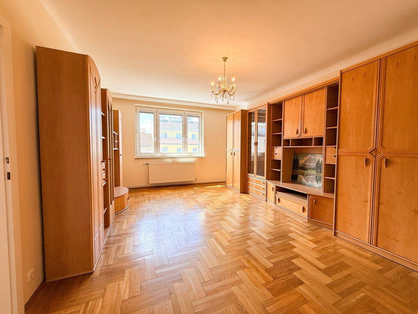 Geräumiges Zimmer mit Parkettboden und umfangreichen Einbauschränken entlang der Wände.