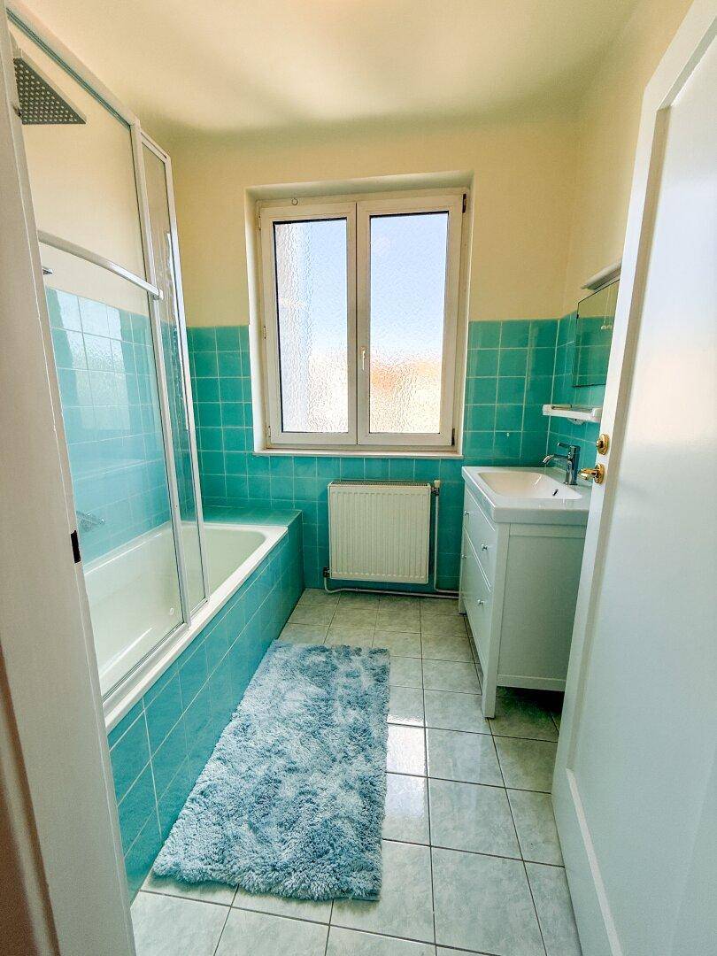 Badezimmer mit Badewanne, Dusche, Waschbecken und einem Fenster für Tageslicht.