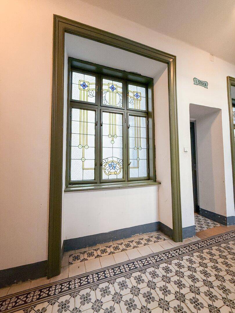 Historisches Buntglasfenster in einem Flur mit dekorativen Fliesen im Gemeinschaftsbereich.
