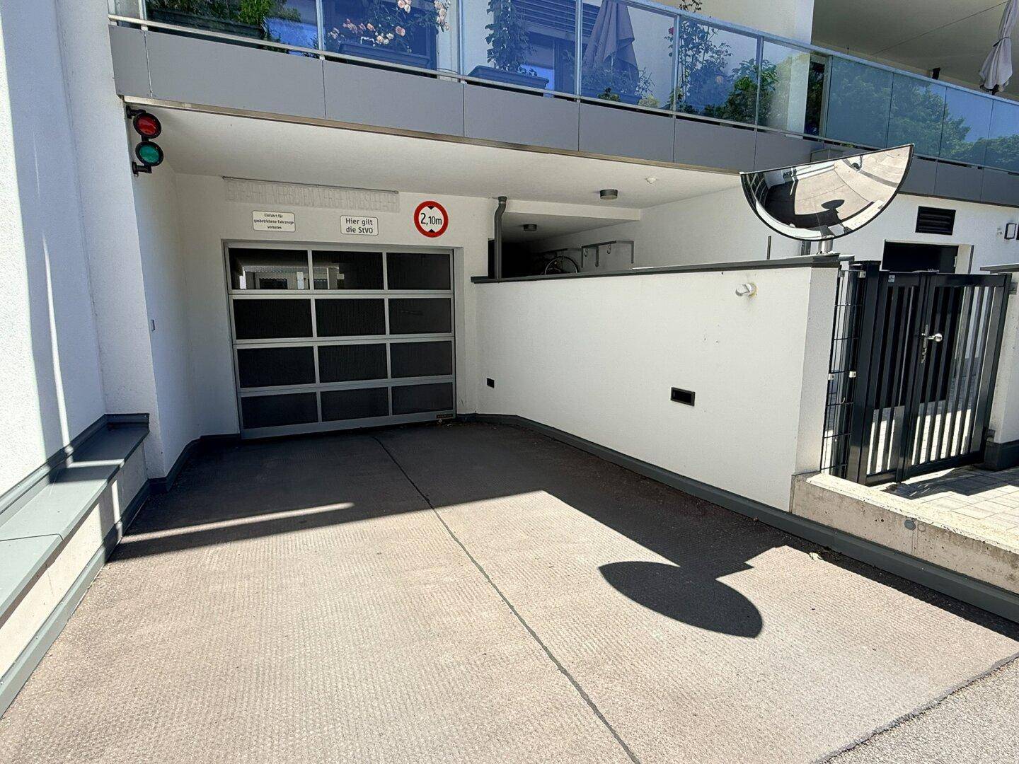 Zufahrt zur Tiefgarage mit Garagentor und Höhenbegrenzung.
